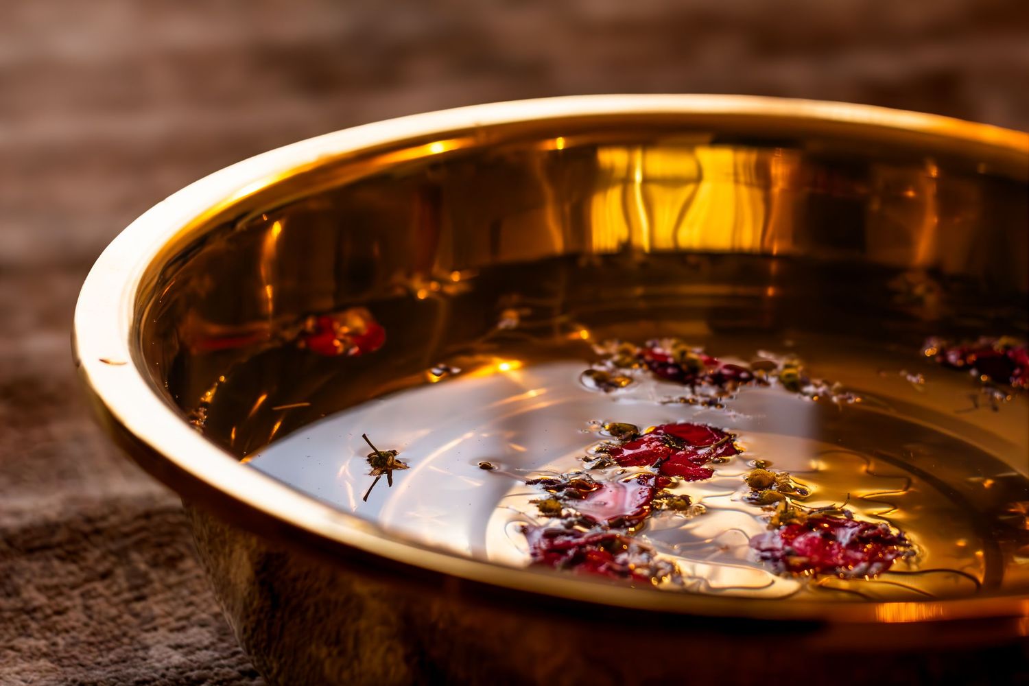 Close-up of a golden bowl with floating rose petals and water creating a serene spa atmosphere.