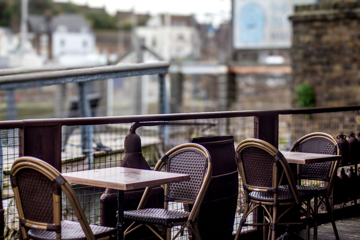 Empty cafe terrace with wicker chairs and tables on a cloudy day.