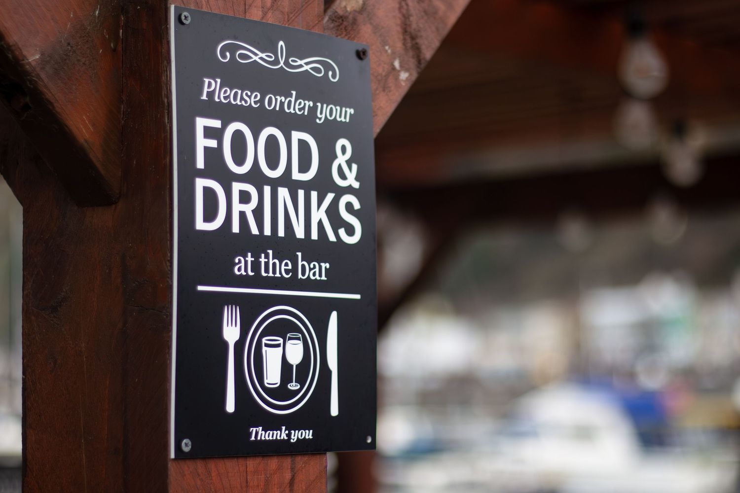 Black and white signage for food and drinks mounted on a wooden wall.