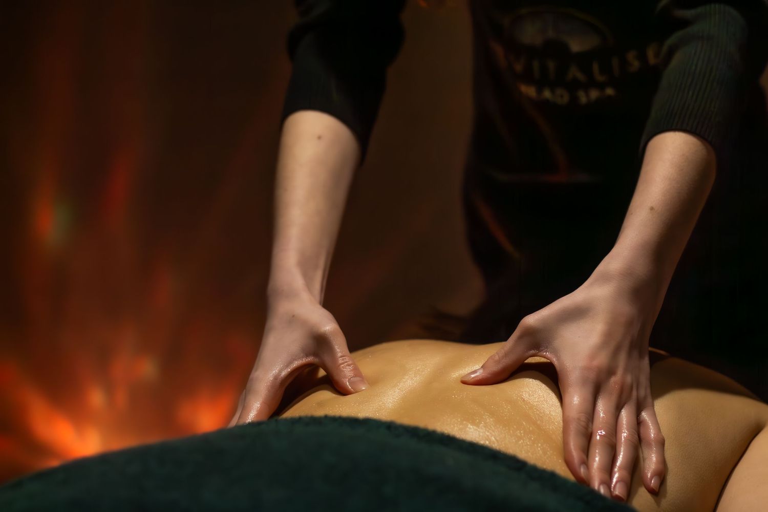 Hands performing therapeutic massage treatment in warm ambient lighting.