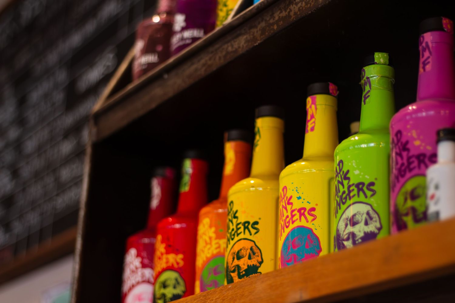 Colorful bottles of drinks lined up on a shelf with vibrant lighting.
