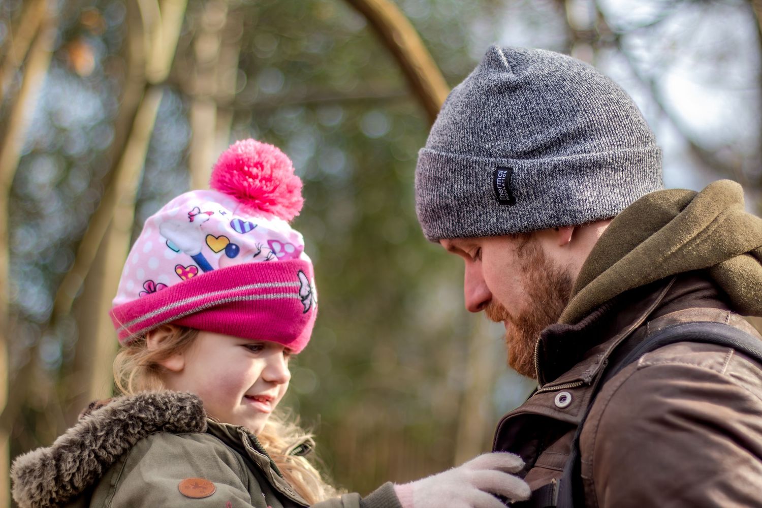 Two people share a warm winter moment outdoors wearing knit hats.