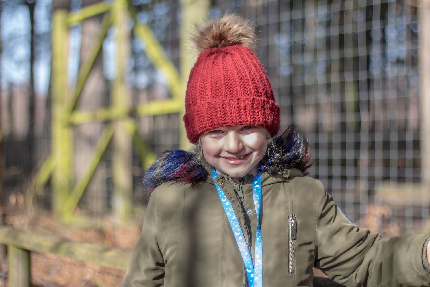 Person wearing a red winter hat and olive jacket outdoors on a cold day.