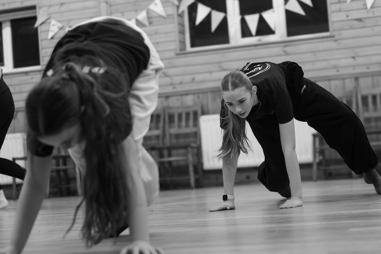 Black and white image of dancers performing low movements in a studio space.