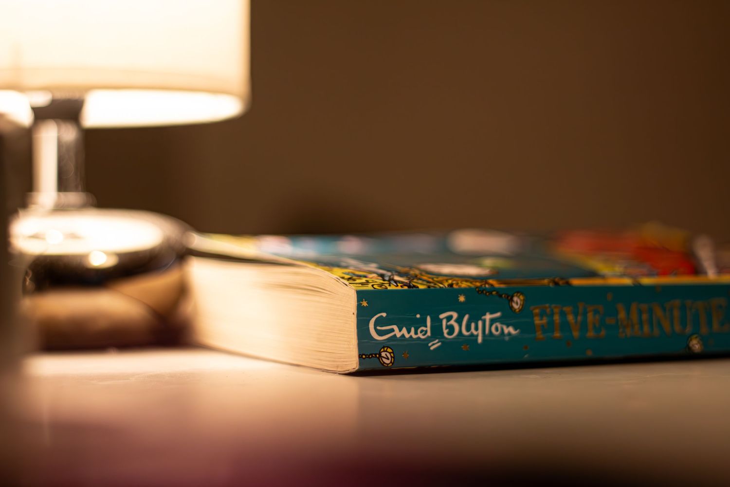 Enid Blyton books and other novels arranged on a wooden surface in dim lighting.