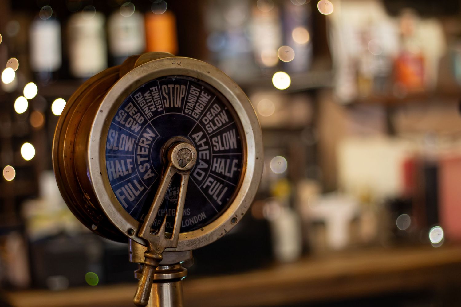 Antique brass ship controls and gauges with bokeh lights in background.