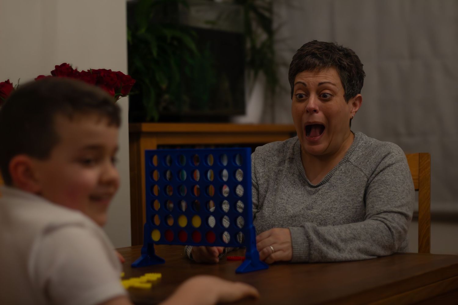 People playing Connect Four board game at a table indoors.