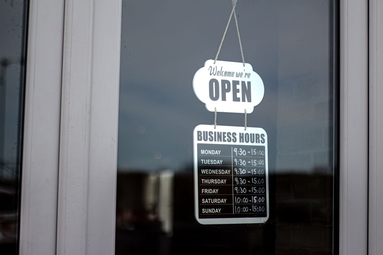 Business hours and open sign displayed in a storefront window.
