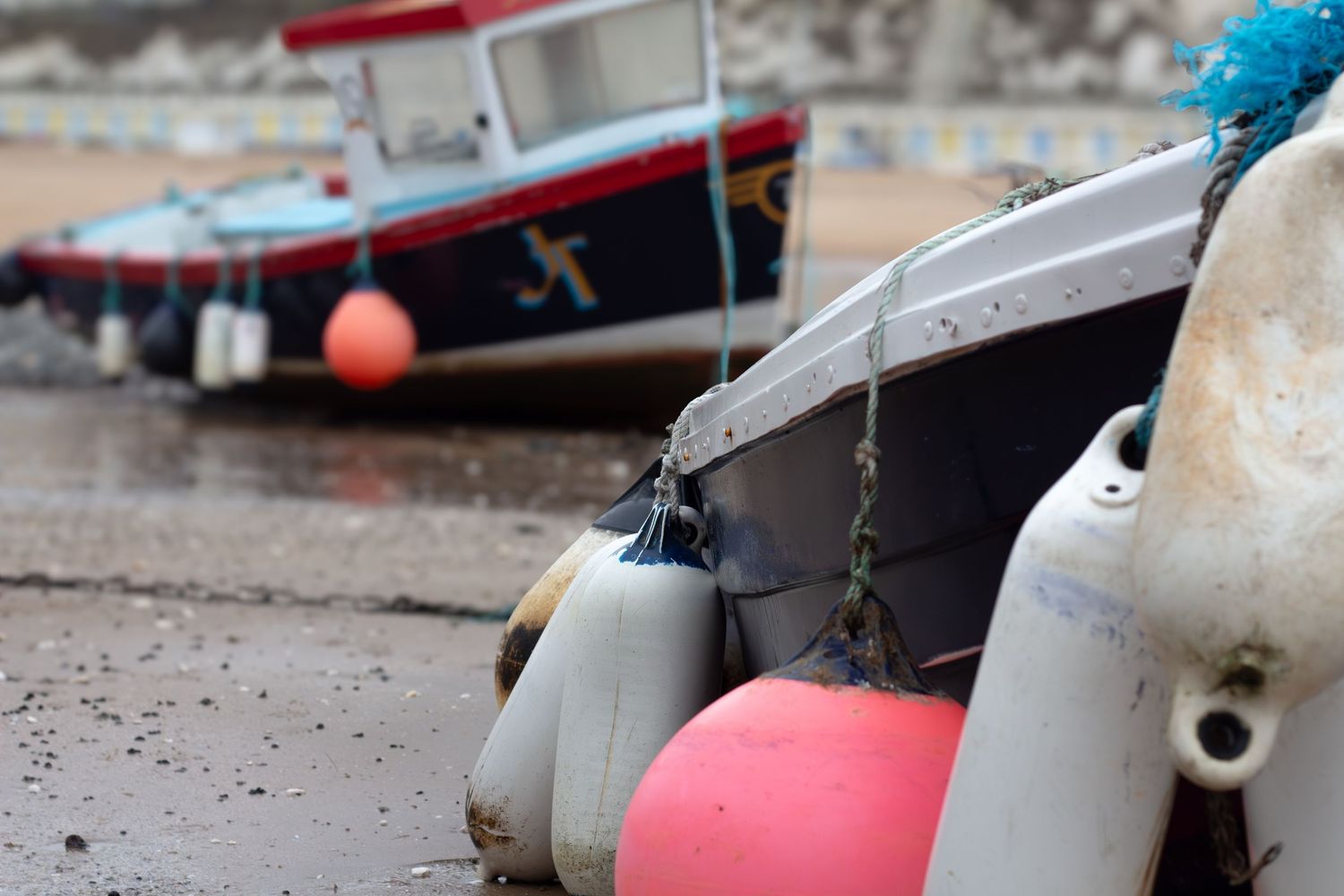 Fishing boats moored at harbor with colorful buoys and ropes in the foreground.