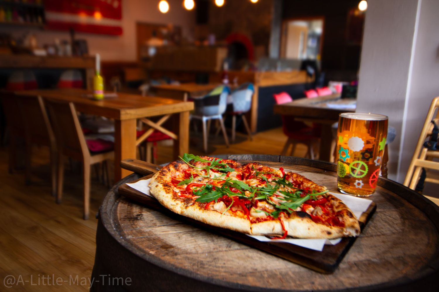 A delicious wood-fired pizza topped with fresh herbs and tomatoes served on a rustic wooden board in a restaurant.