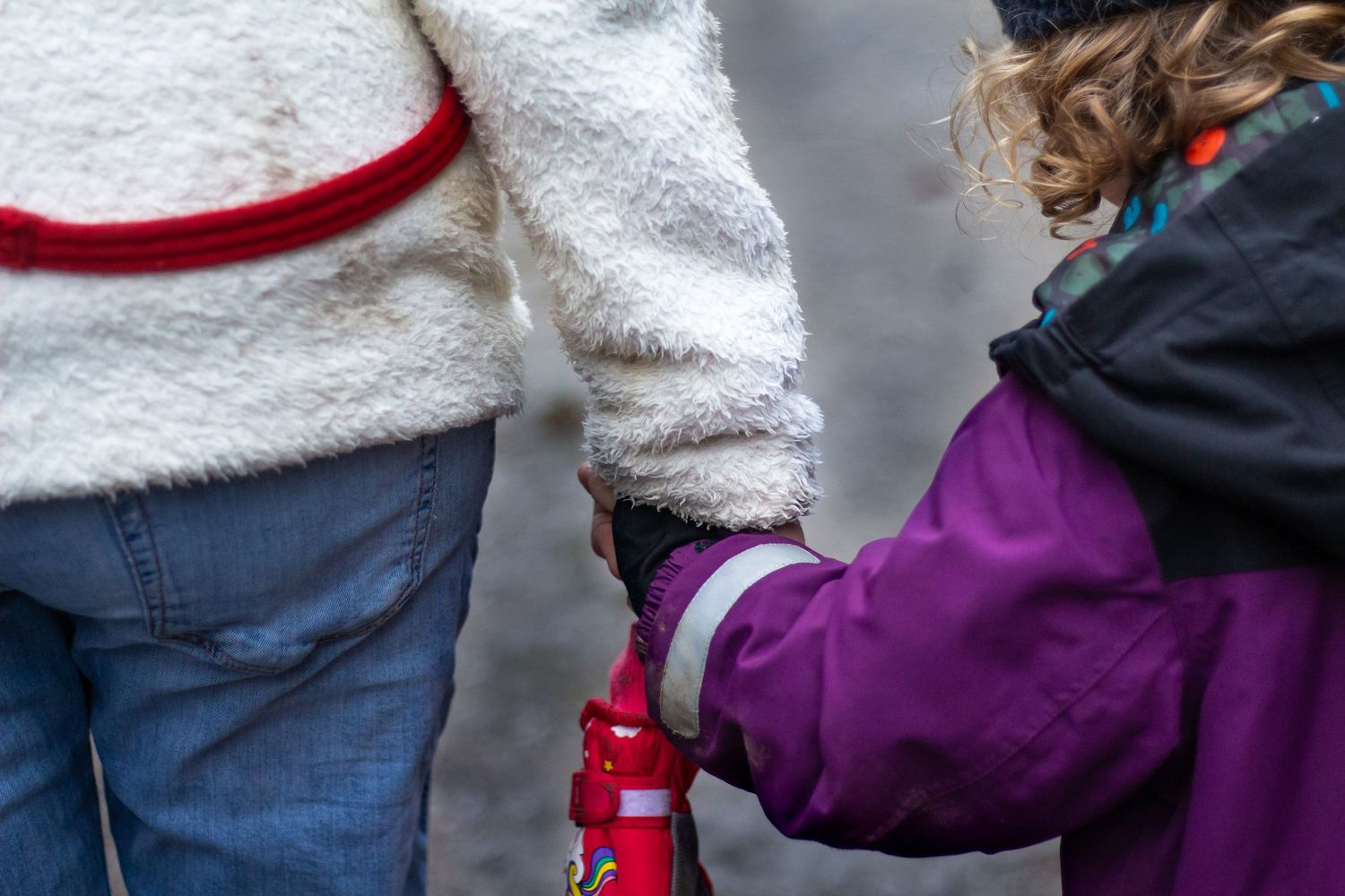 People holding hands while walking together outdoors.