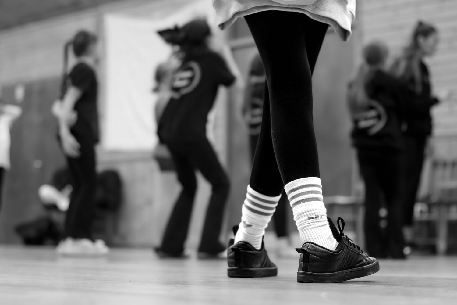 Black and white image of dancers' feet during practice with striped socks.