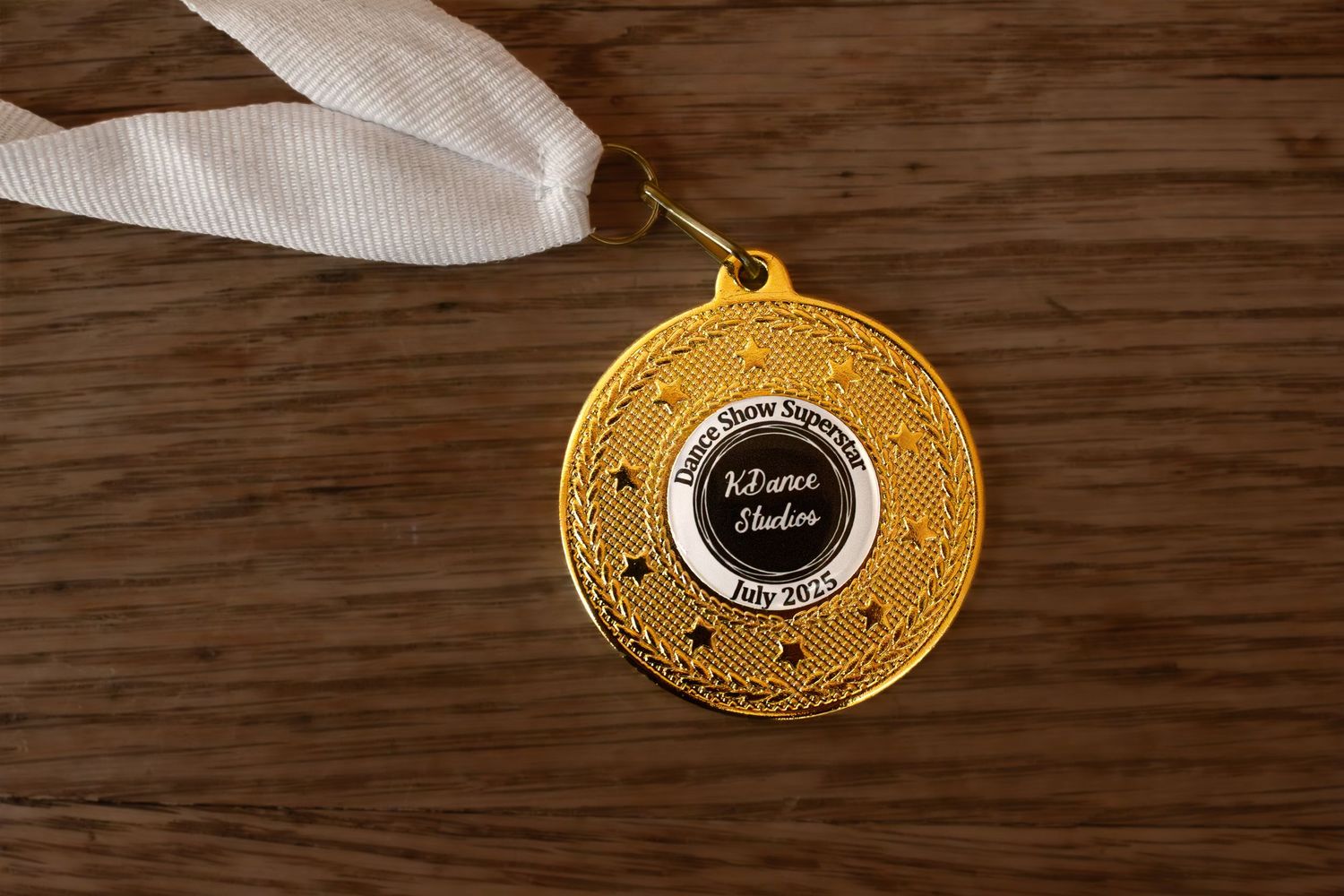 Gold dance competition medals with black centers displayed on wooden surface.