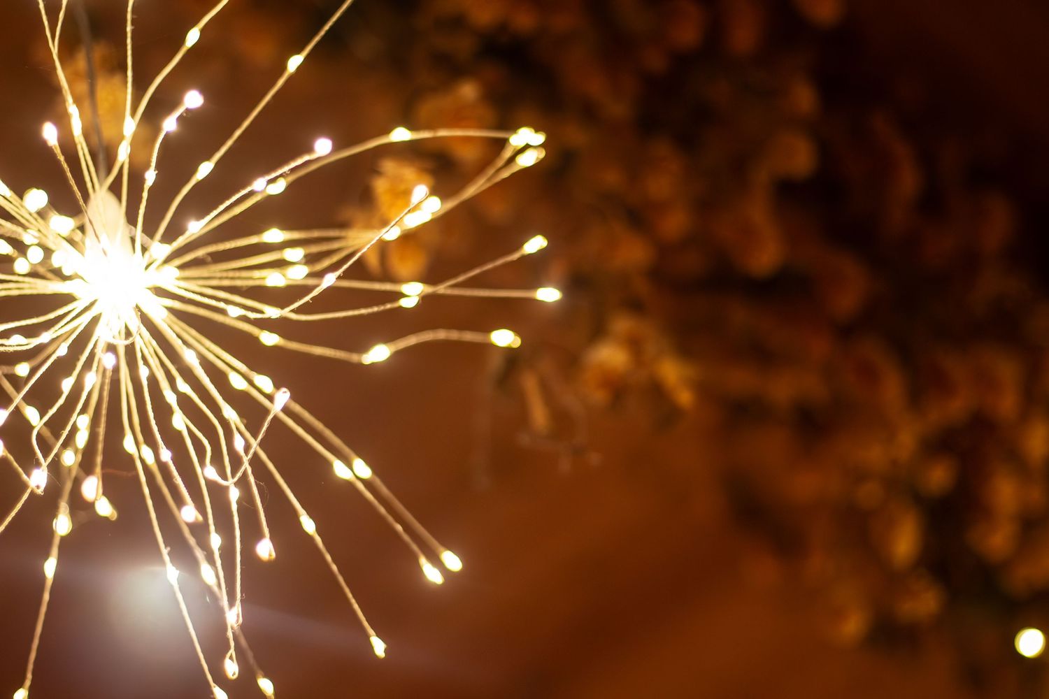Golden sparklers creating bright light trails against a dark background.