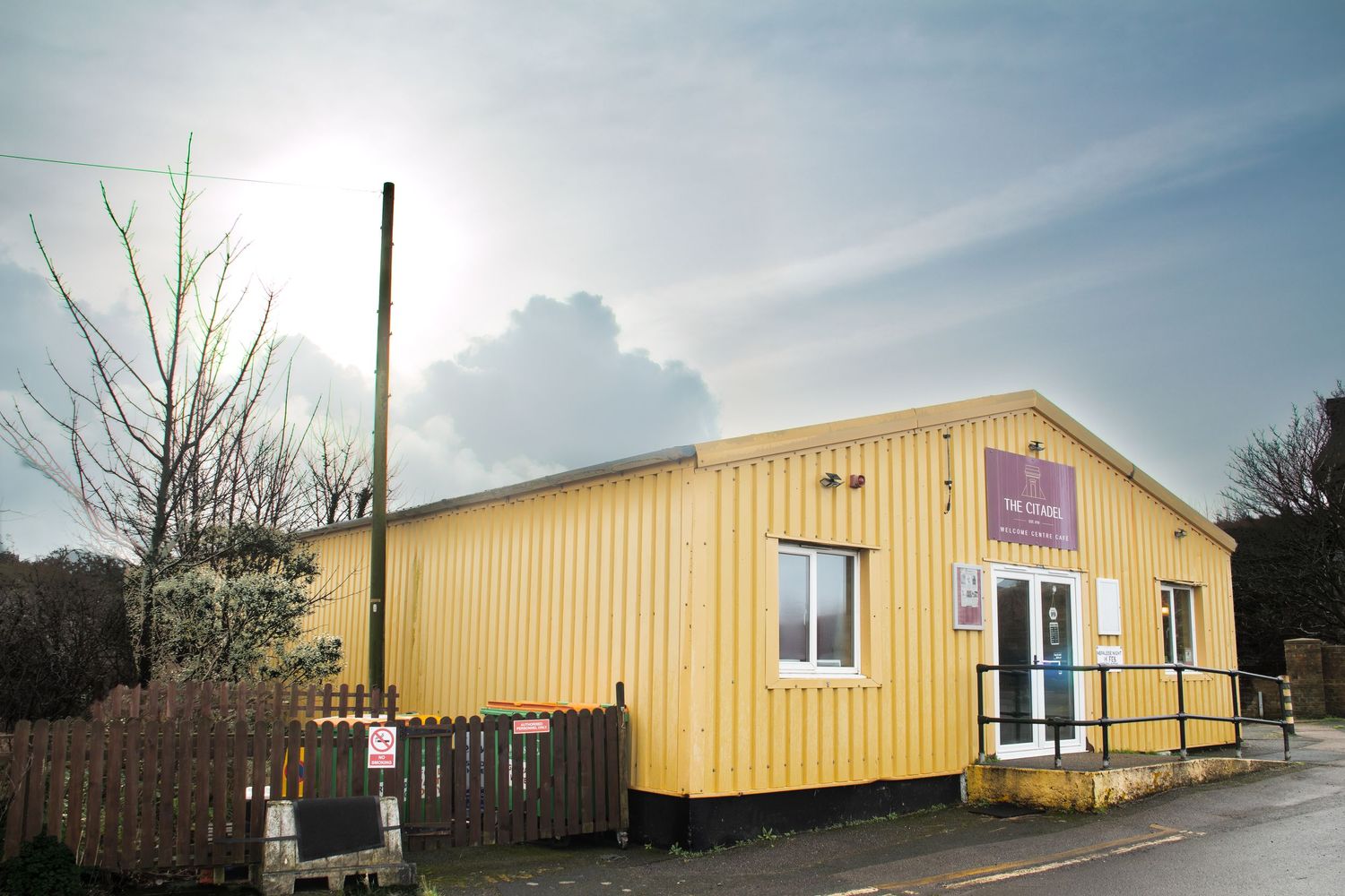 Exterior view of a long yellow commercial building with white trim on an overcast day.