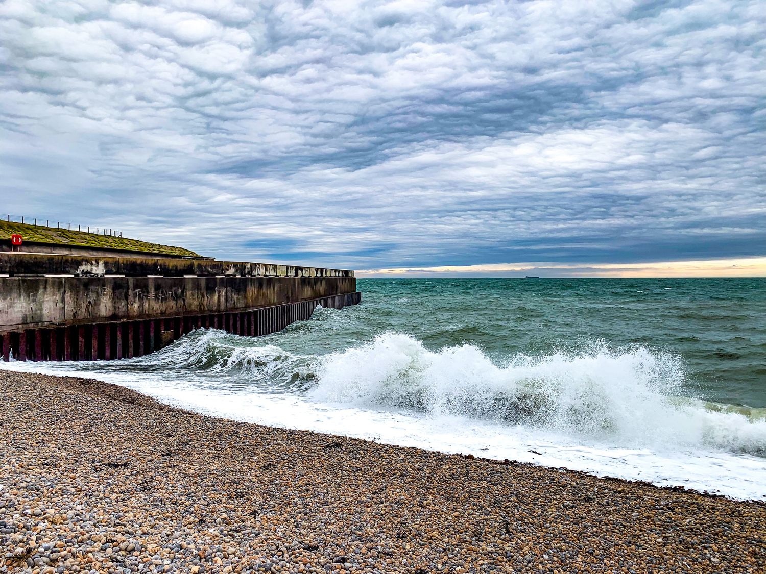Rocky beach shoreline with dramatic waves crashing against pebbled coast.