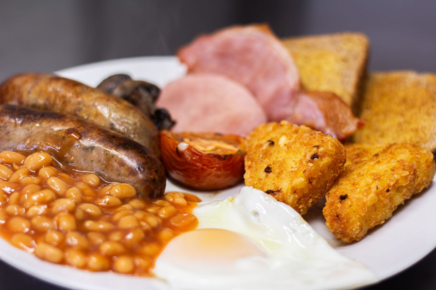Traditional English breakfast with beans, eggs, and toast served on a white plate.