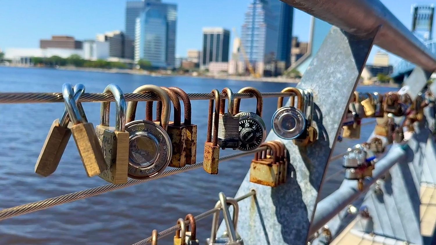 Close-up of nautical dock cleats and ropes against urban waterfront backdrop.