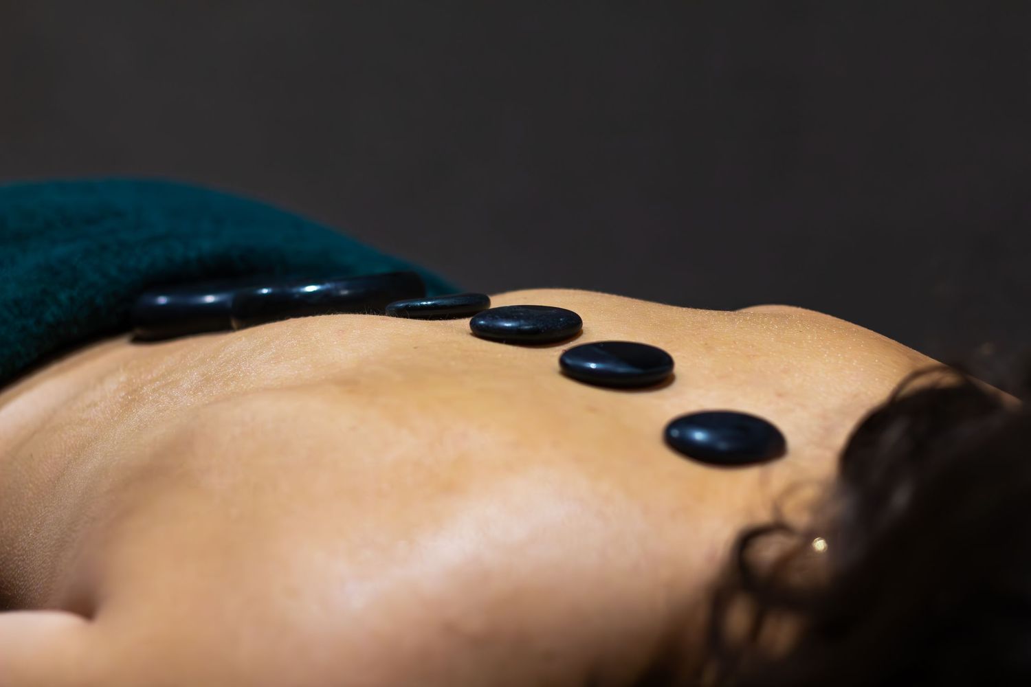 Hot stones lined up on a person's back during a spa treatment.