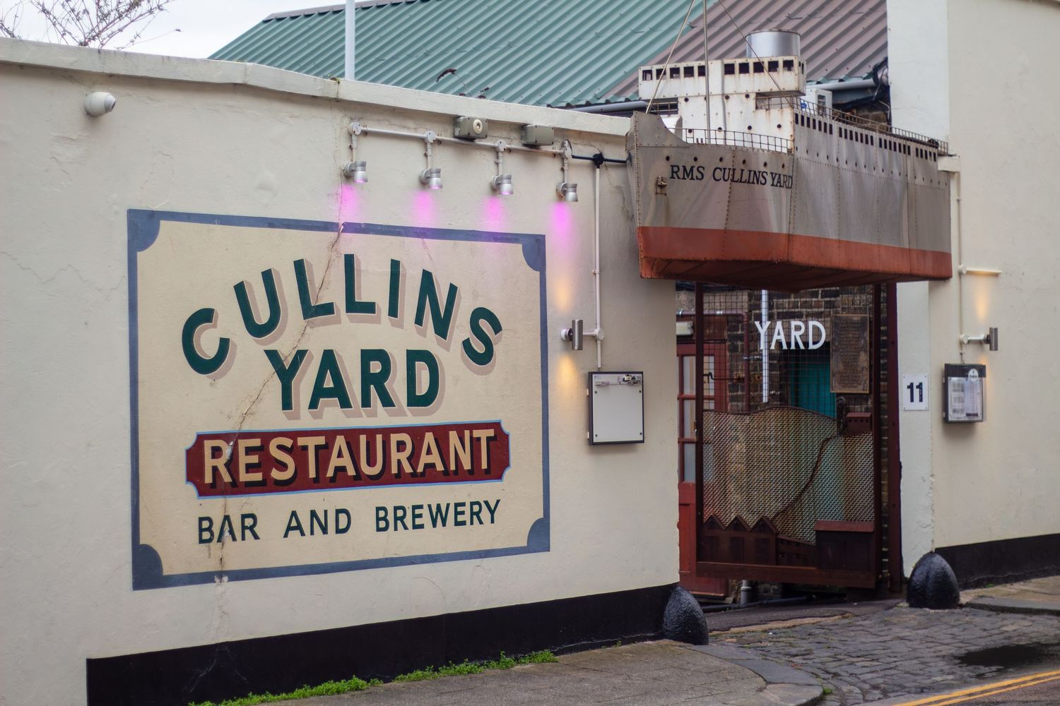 Exterior view of Collins Yard Bar and Brewery with restaurant signage visible.