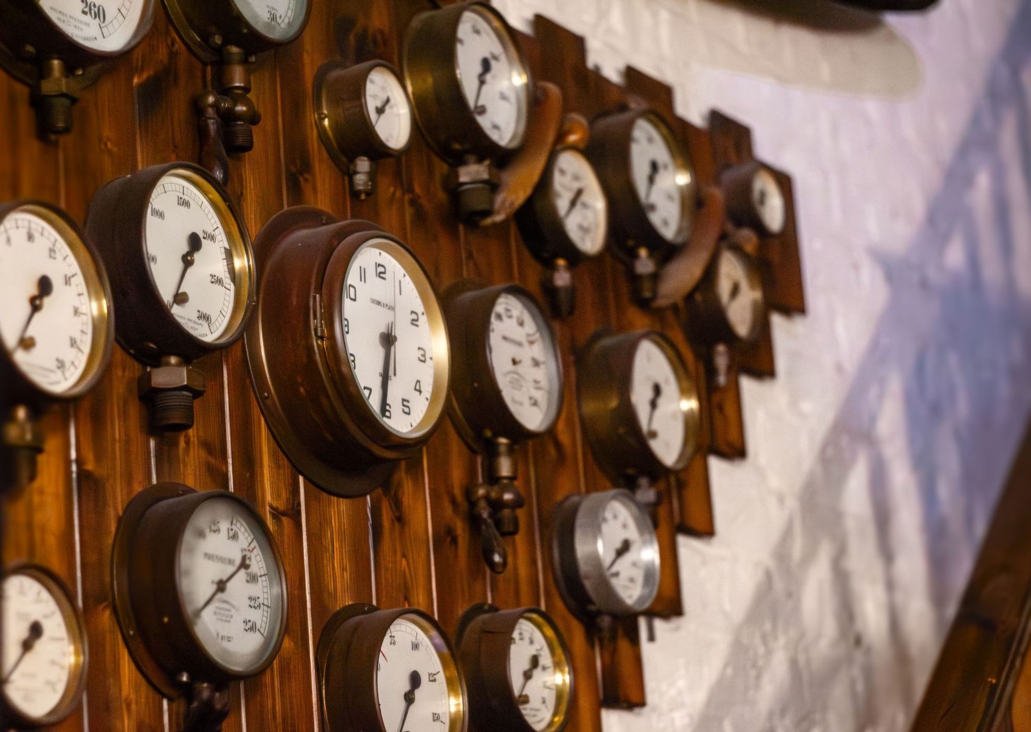Row of vintage pressure gauges mounted on wooden panel with industrial aesthetic.
