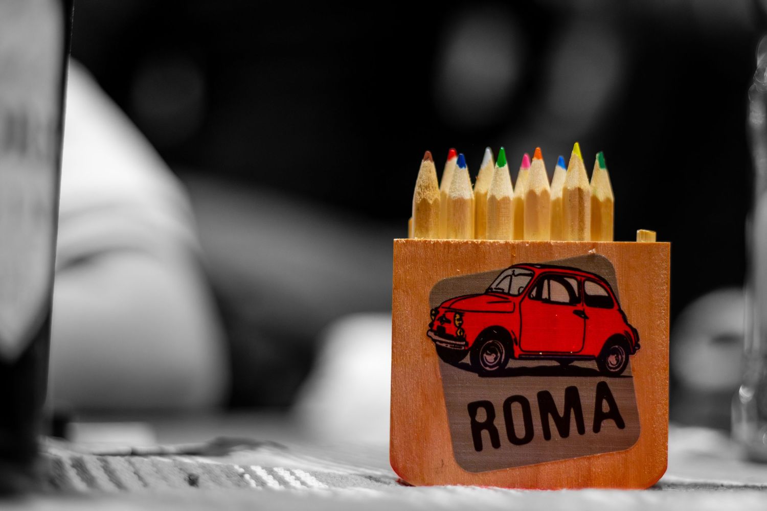 Wooden display with colorful pencils and vintage car decoration in selective focus.