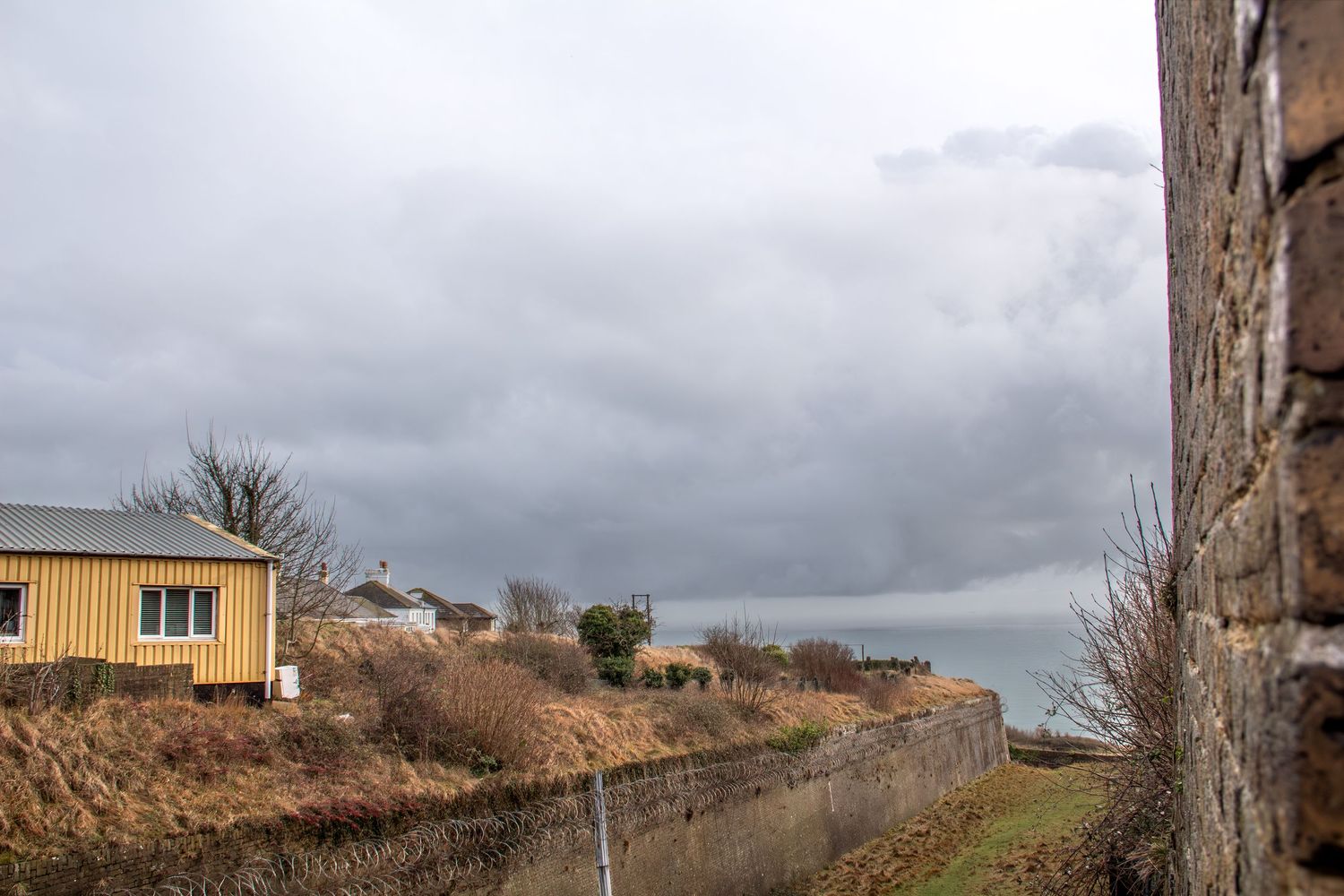 Panoramic view of a yellow building on a hill under cloudy skies.