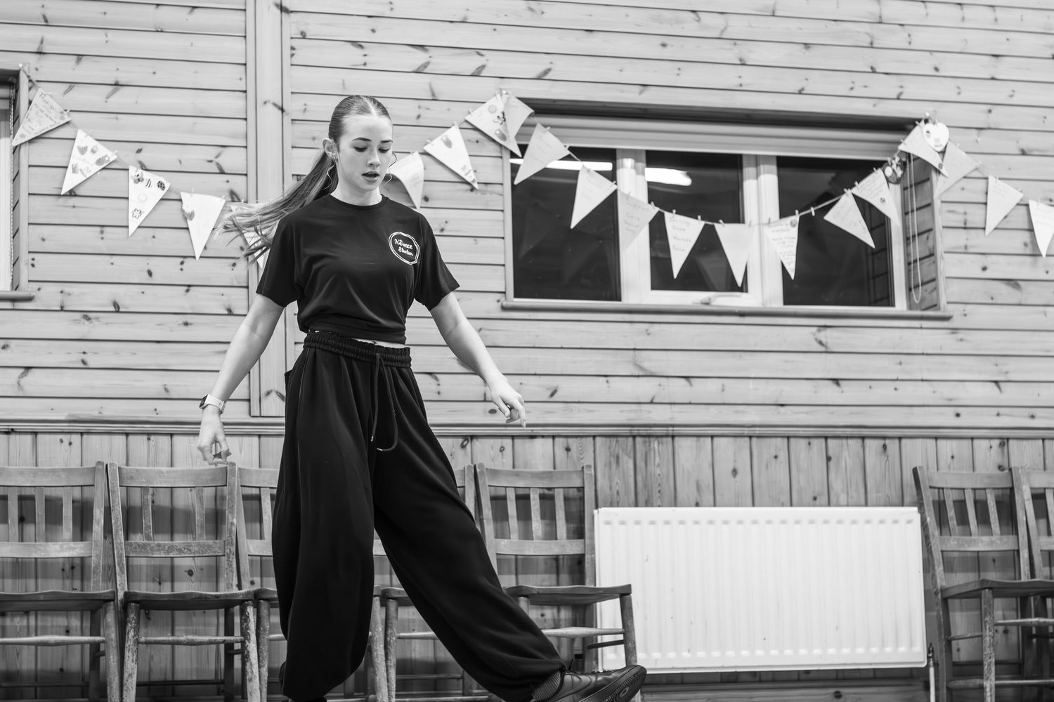 Dancers practicing in a studio with white walls and decorative bunting.