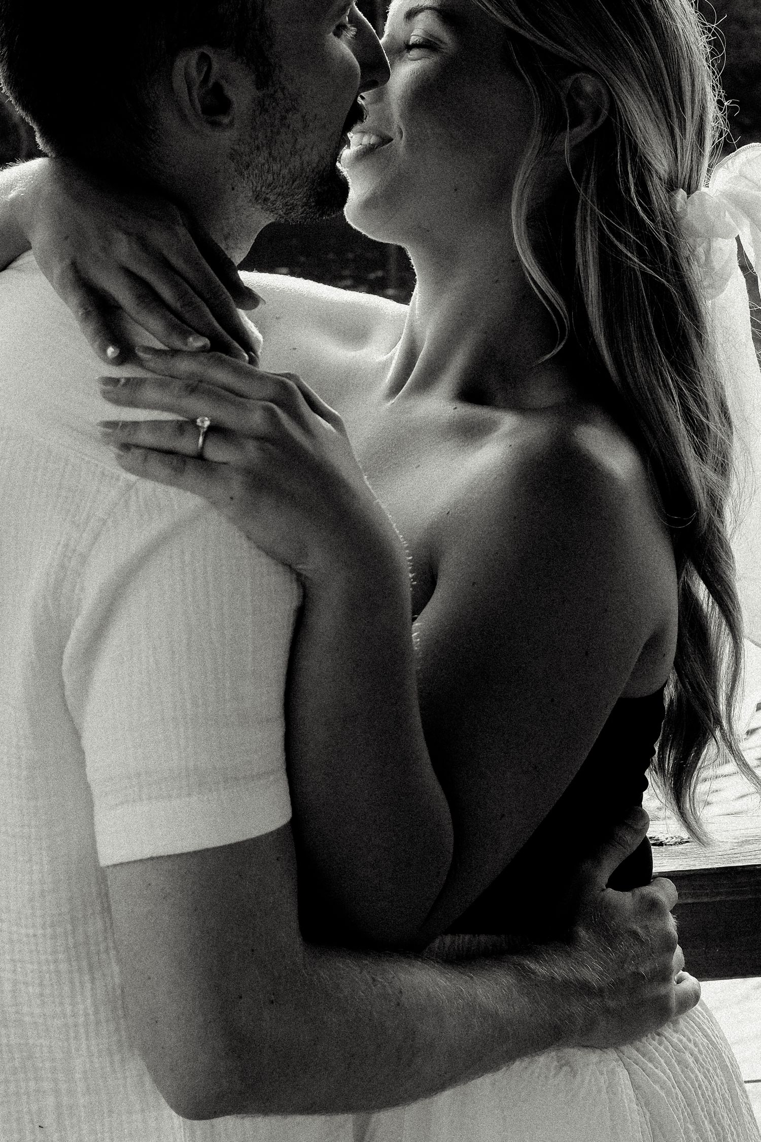 Black and white romantic photo of couple embracing and laughing together closely.