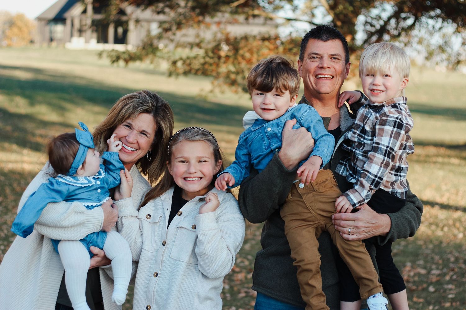 Smiling family of six enjoying a sunny fall day outdoors near a rustic barn Zionsville family photographer Regan Nichalson Creative