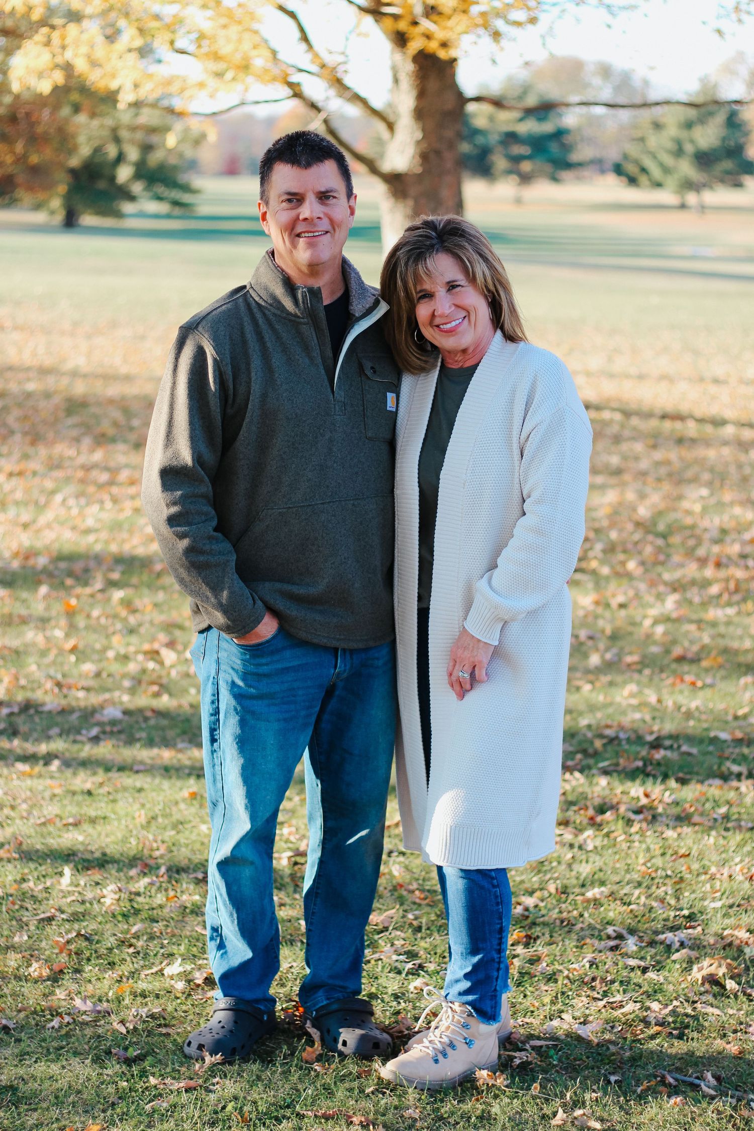 Happy couple standing together in a sunny park surrounded by fall foliage Zionsville family photographer Regan Nichalson Creative