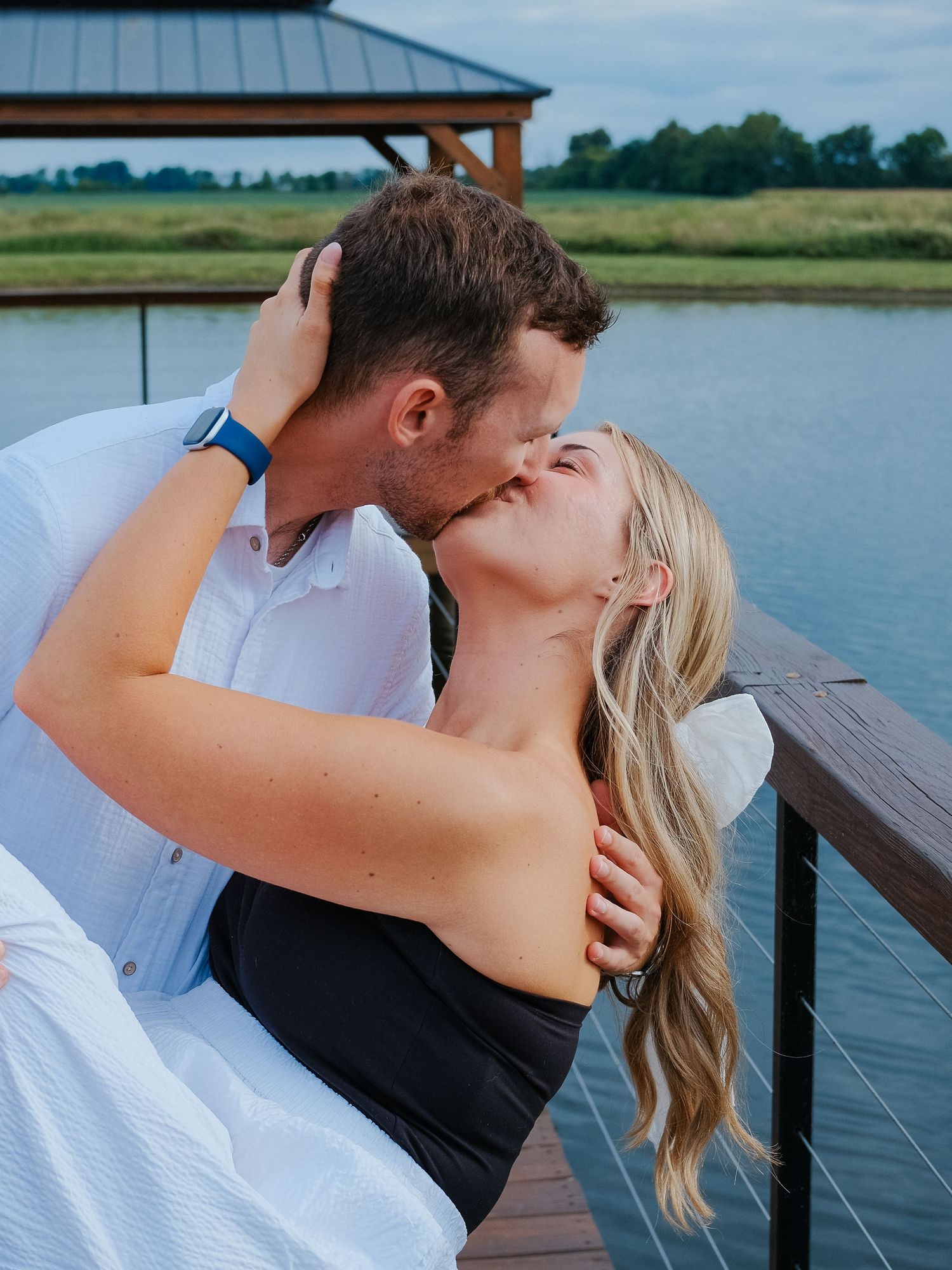 Passionate couple kissing on lakeside dock with gazebo and lush green landscape Hamilton County couples photographer Regan Nichalson Creativ