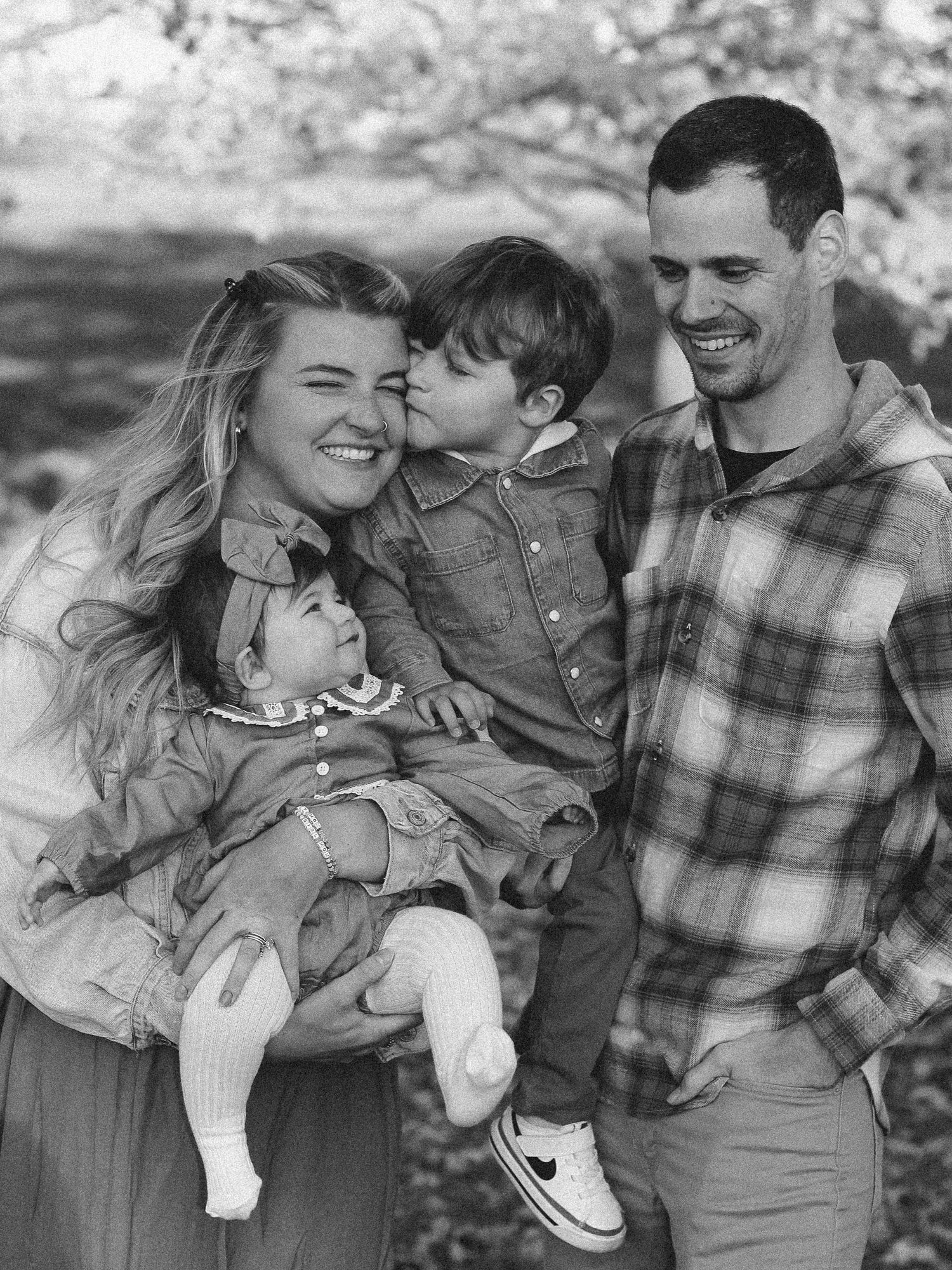 Black and white portrait of a happy family of four sharing a joyful moment outdoors Zionsville family photographer Regan Nichalson Creative