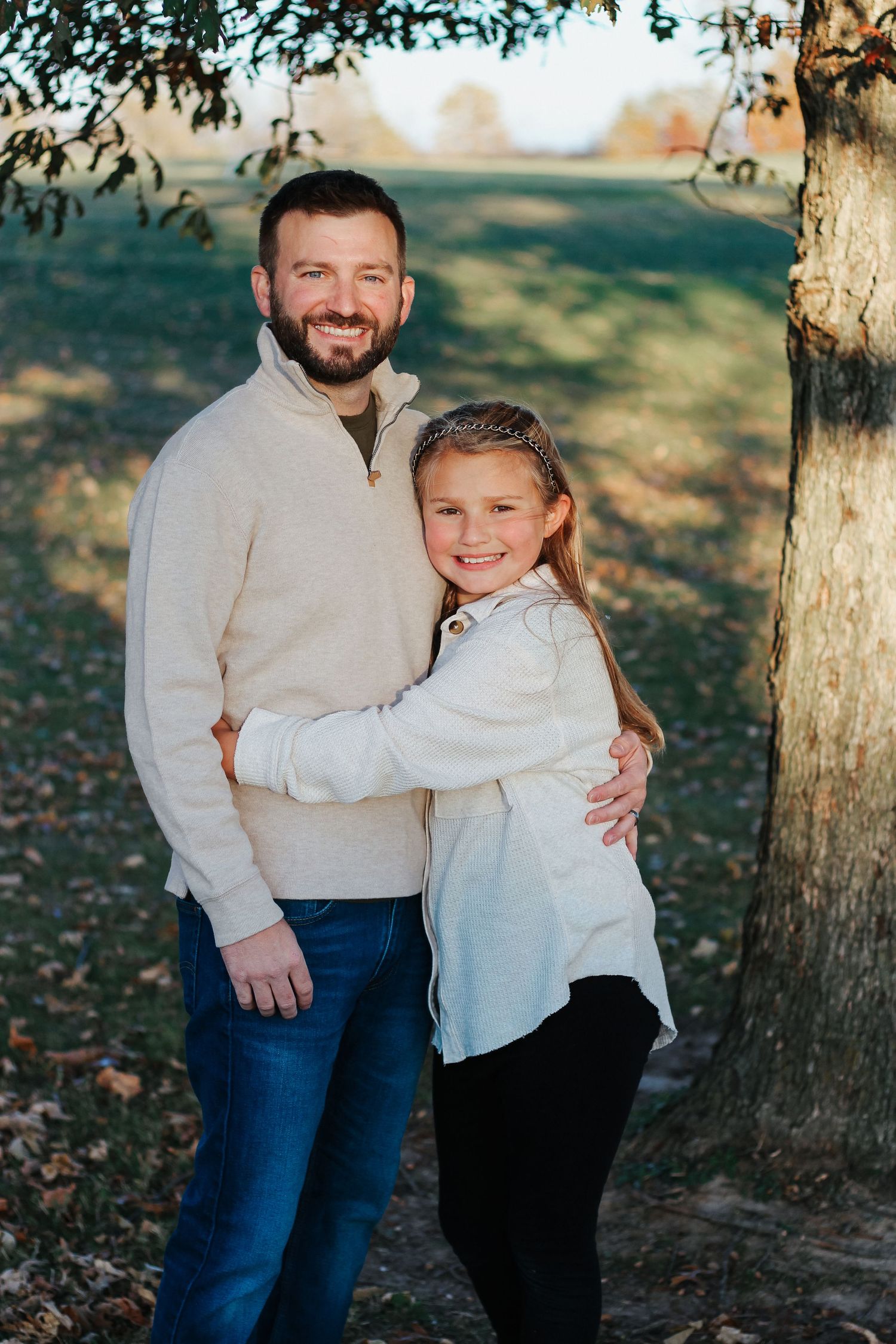 Happy father and daughter embracing and smiling together near a tree Zionsville family photographer Regan Nichalson Creative