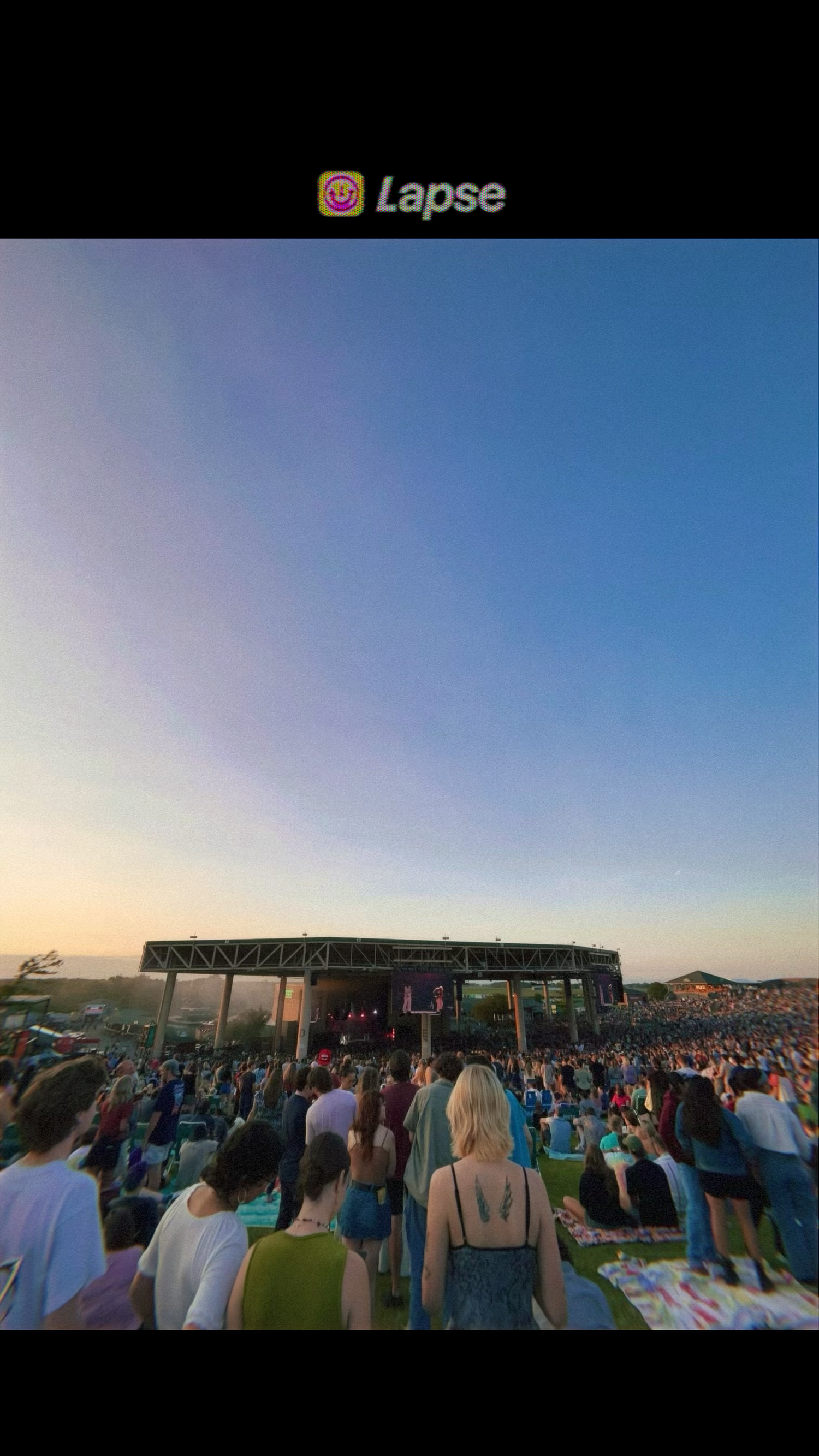 Large outdoor music festival crowd watching a stage performance at sunset under a vivid blue sky. Carmel family photographer Regan Nichalson