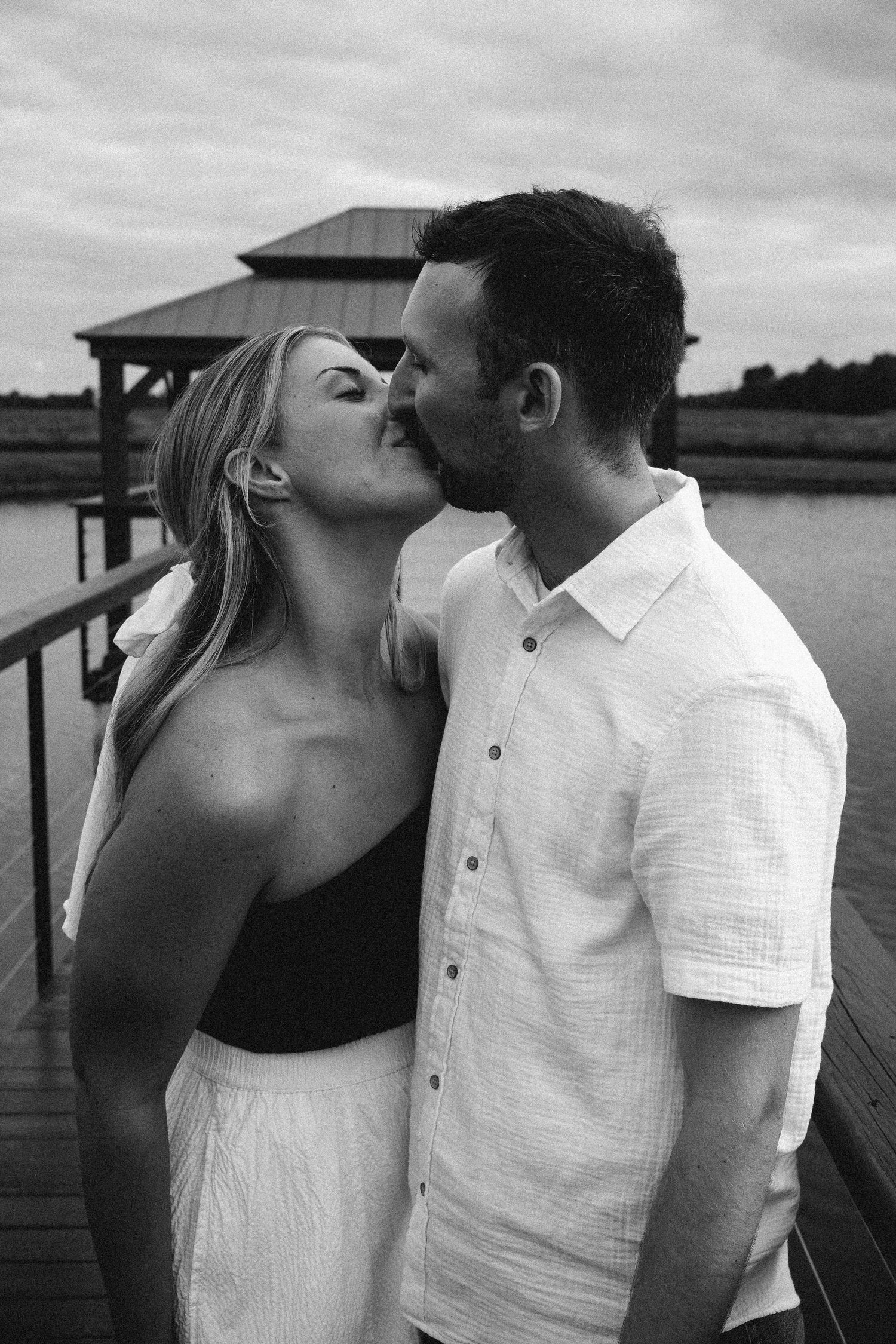 Romantic black and white photo of a couple kissing on a dock with a lakeside Hamilton County couples photographer Regan Nichalson Creative