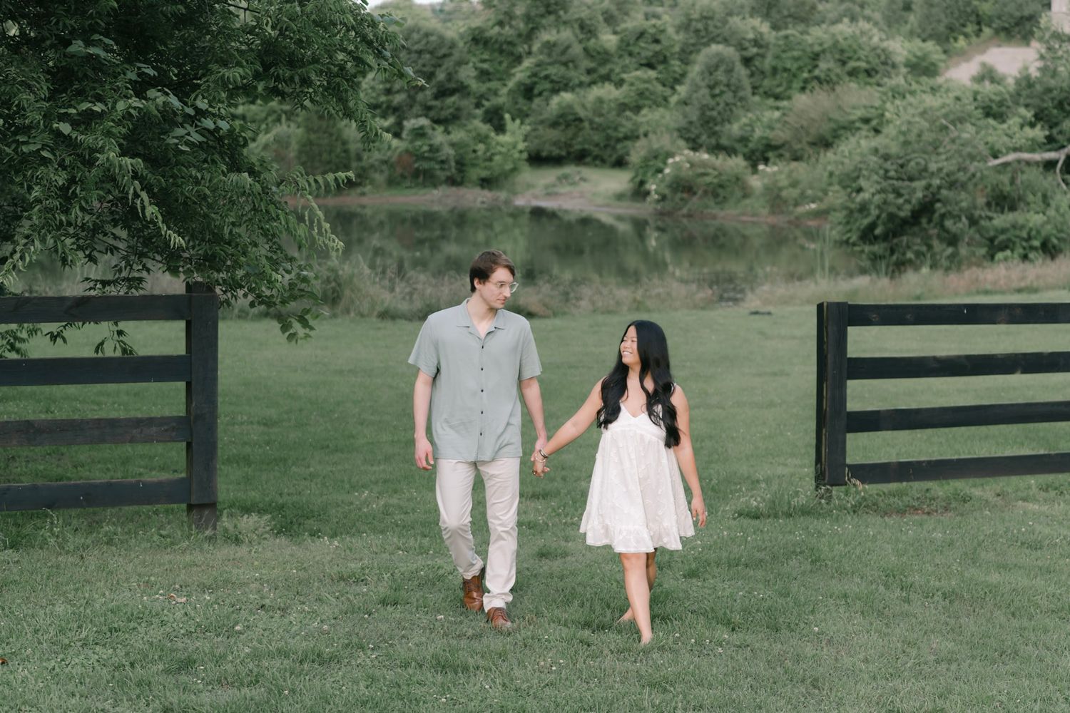 engaged couple walking hand in hand through a Tennessee field at sunset