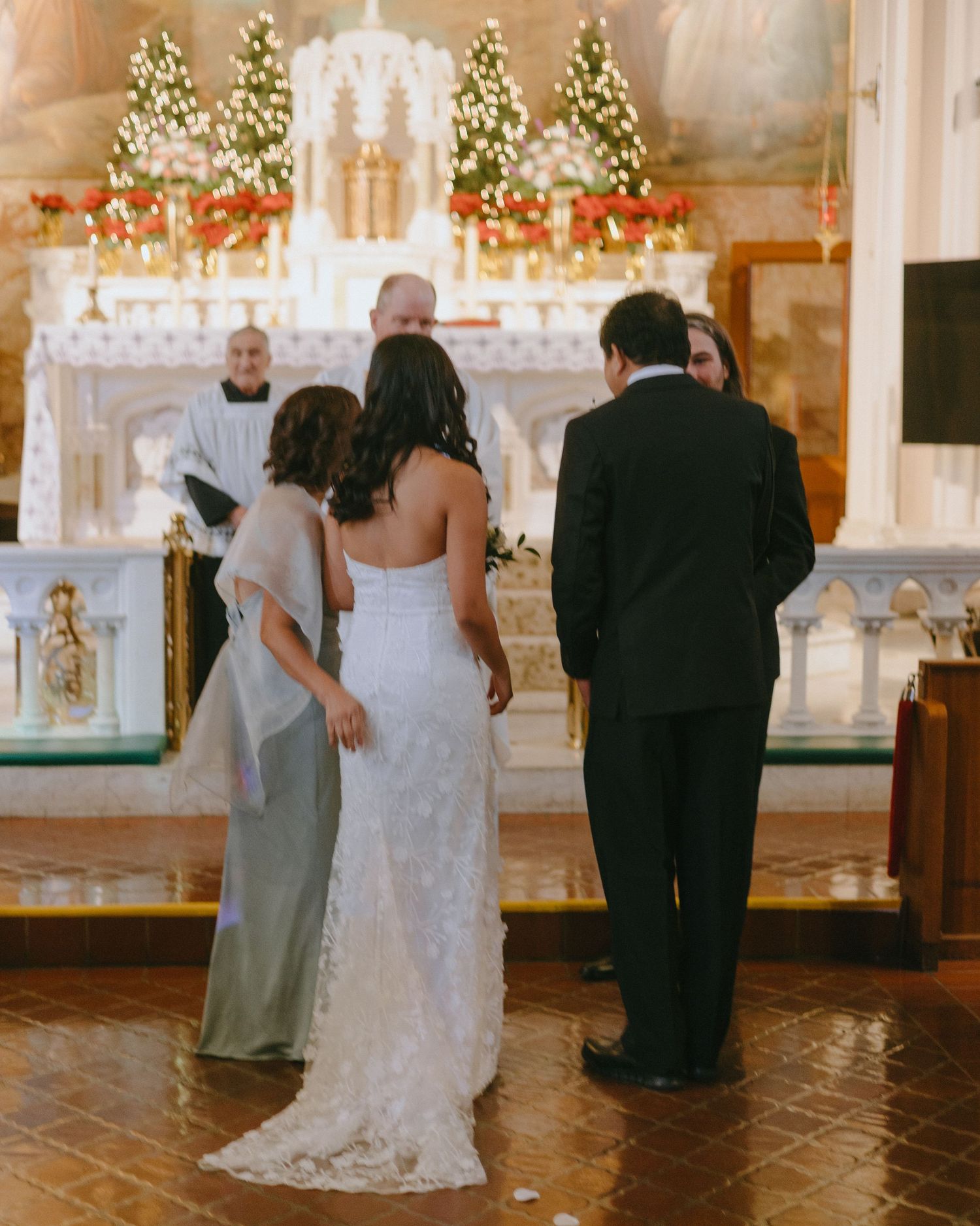 Wedding group walking through ornate church interior with tiled floors and holiday decorations.
