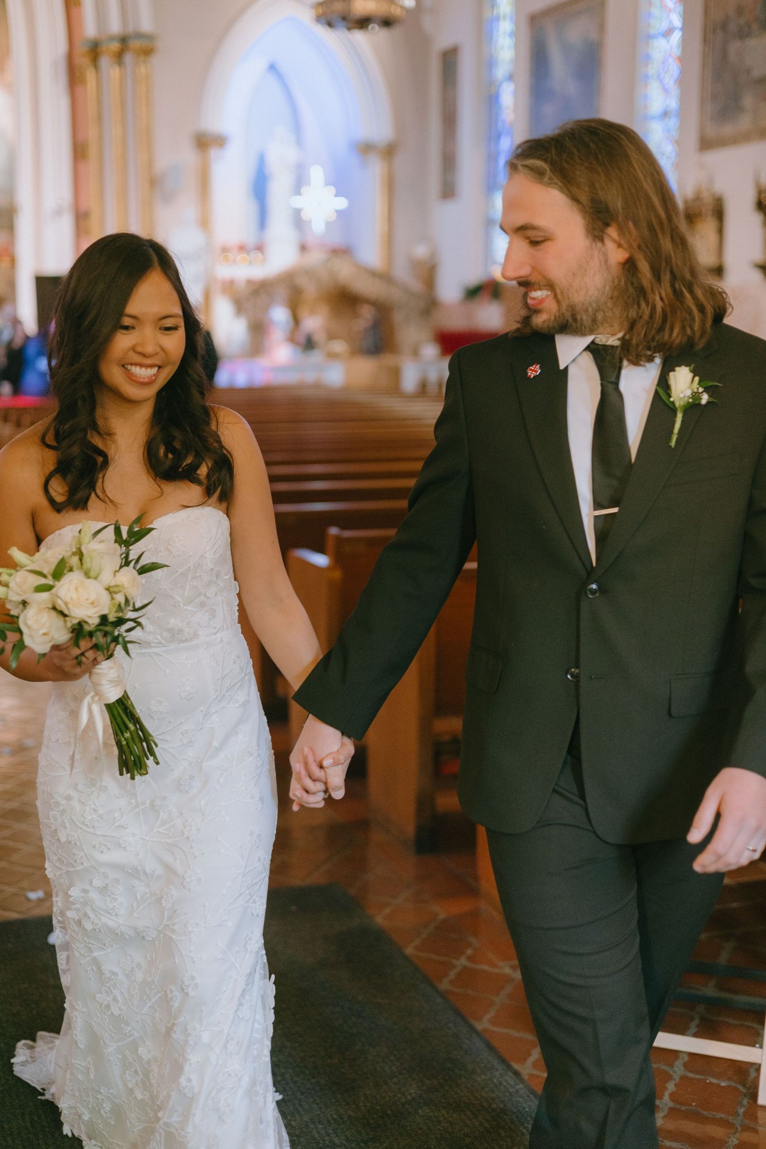 A couple walks down the church aisle together after their wedding ceremony.