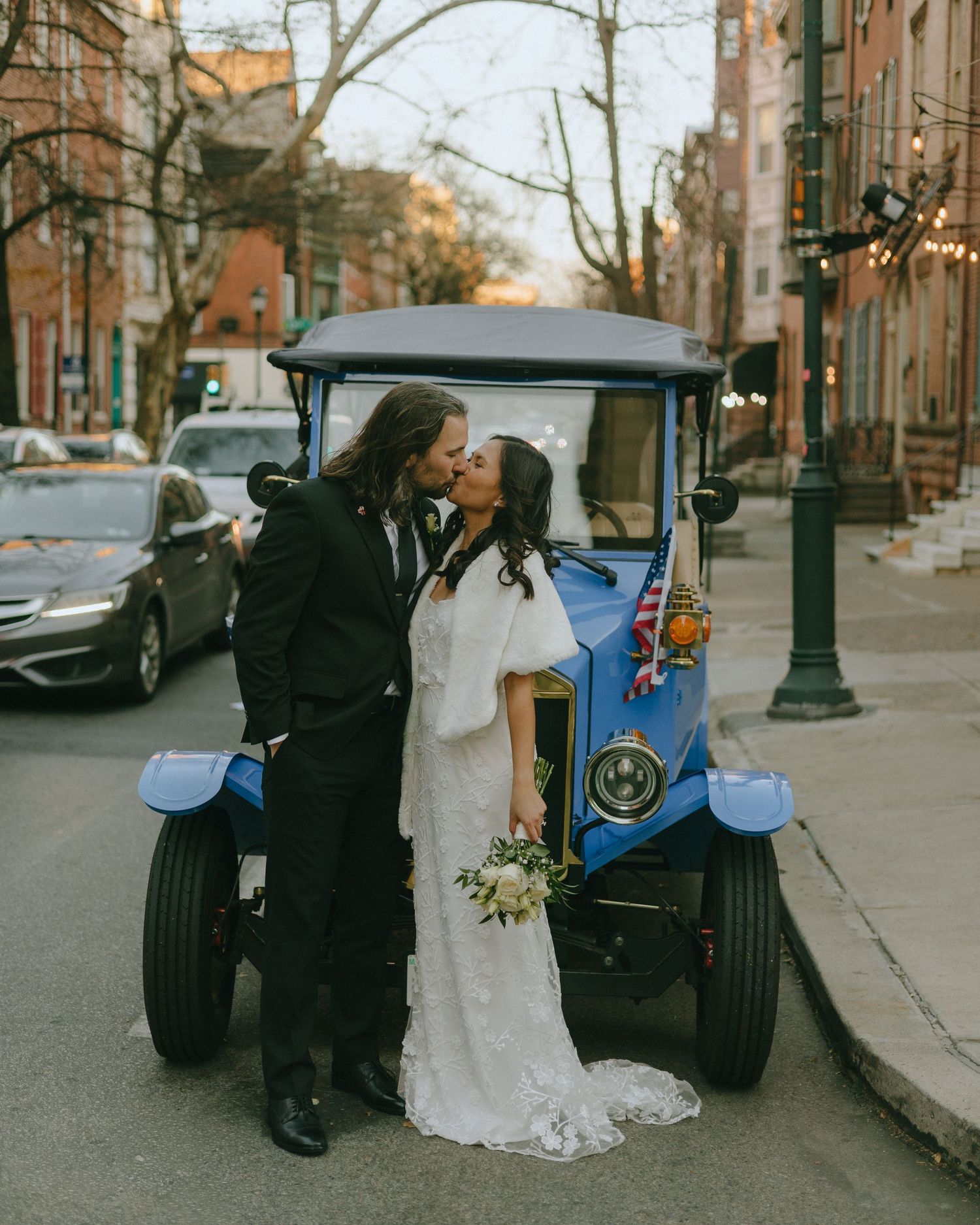 Vintage golf cart adds retro charm to urban wedding photos on tree-lined street.
