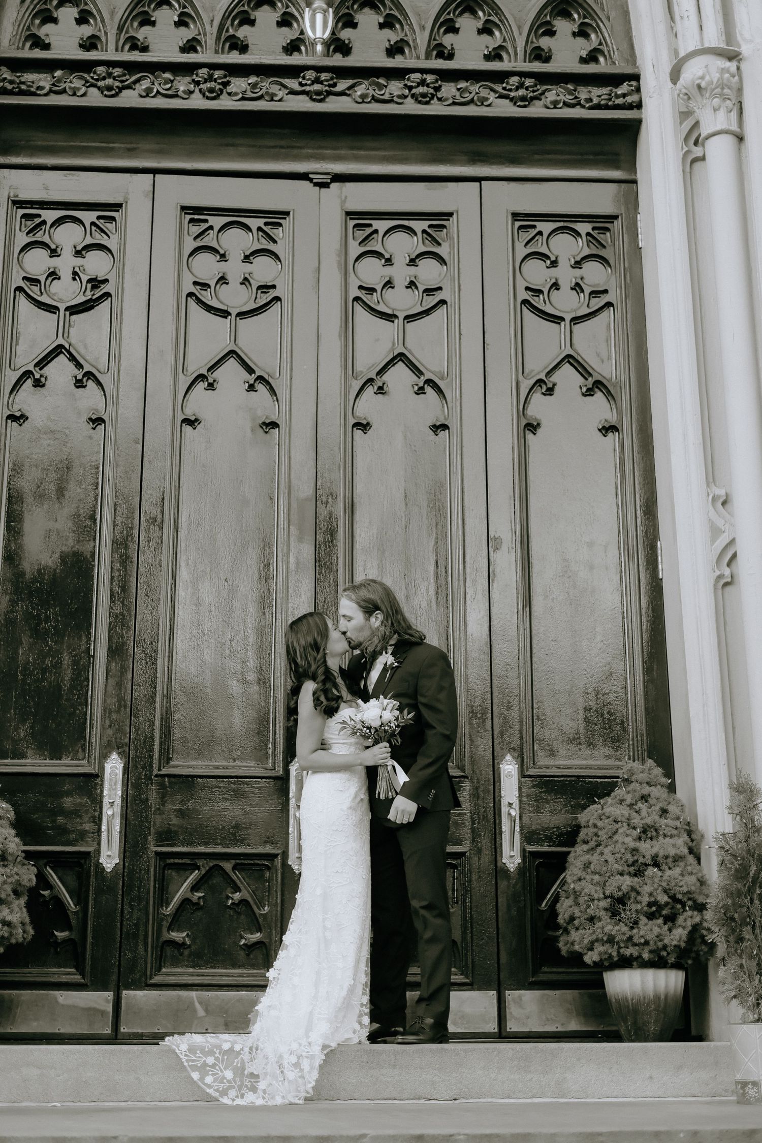Romantic wedding photos taken against gothic architectural details in black and white.