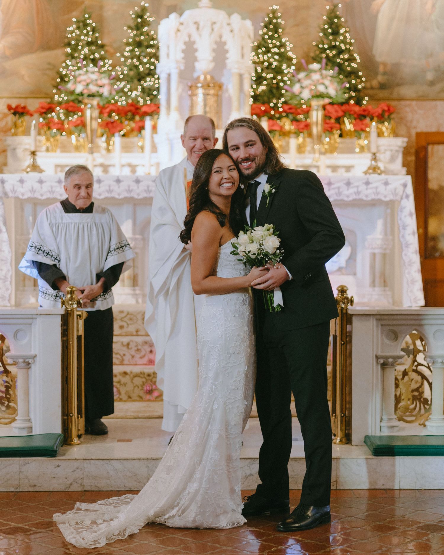 A joyful wedding ceremony procession in a church decorated with holiday lights and greenery.