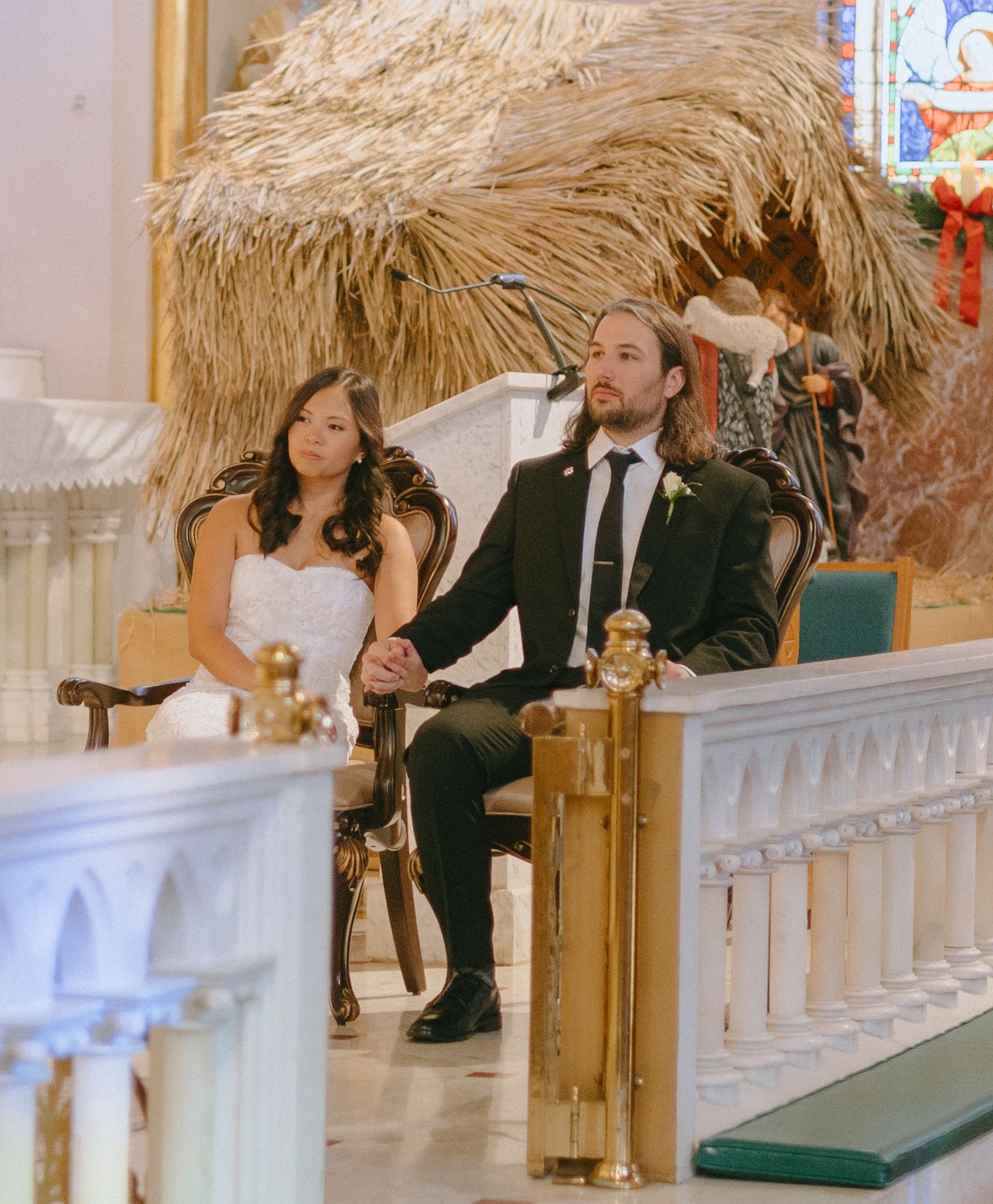 Wedding party seated in ornate church pews during ceremony.