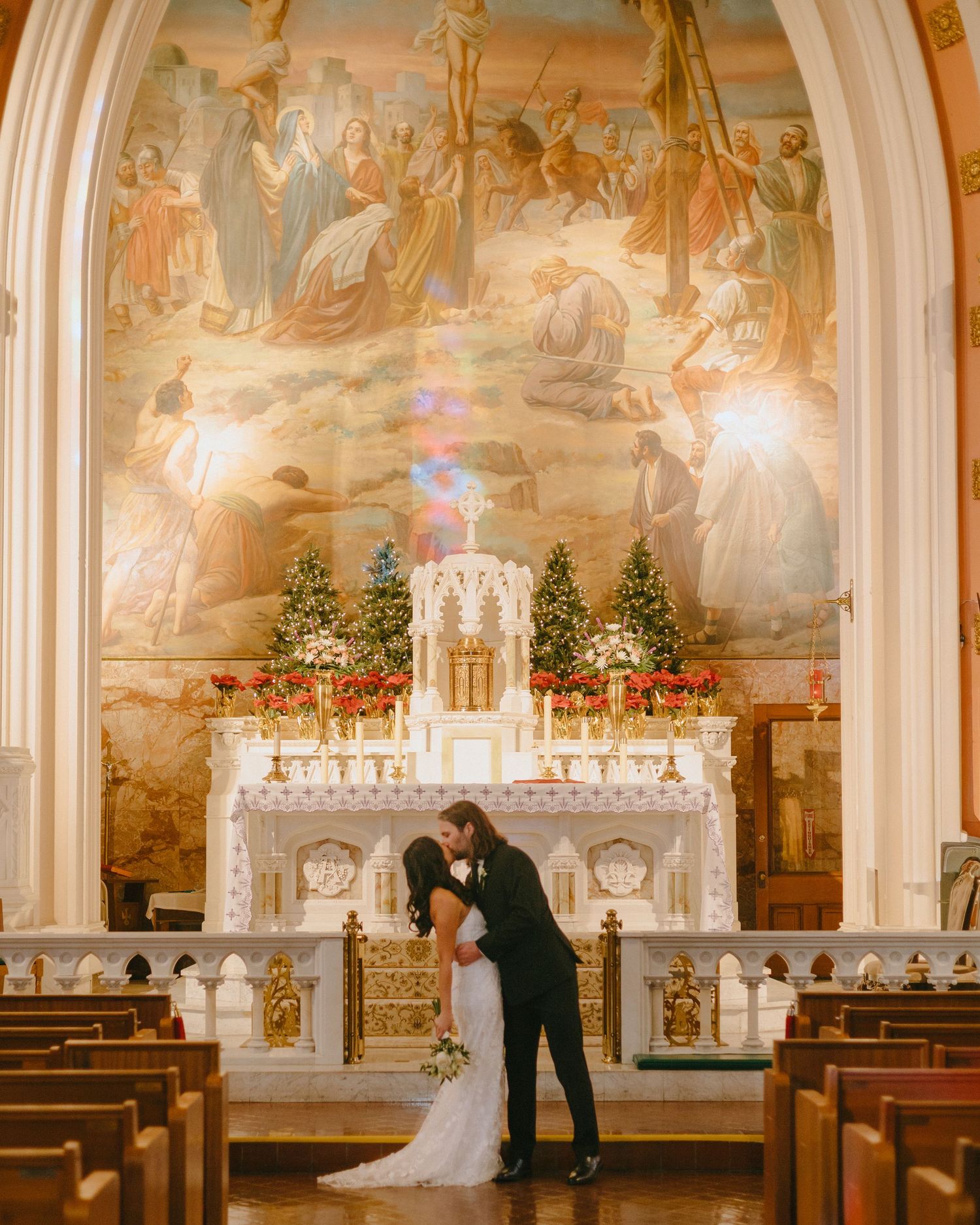 An elegant church interior with painted murals and Christmas decorations during a wedding ceremony.