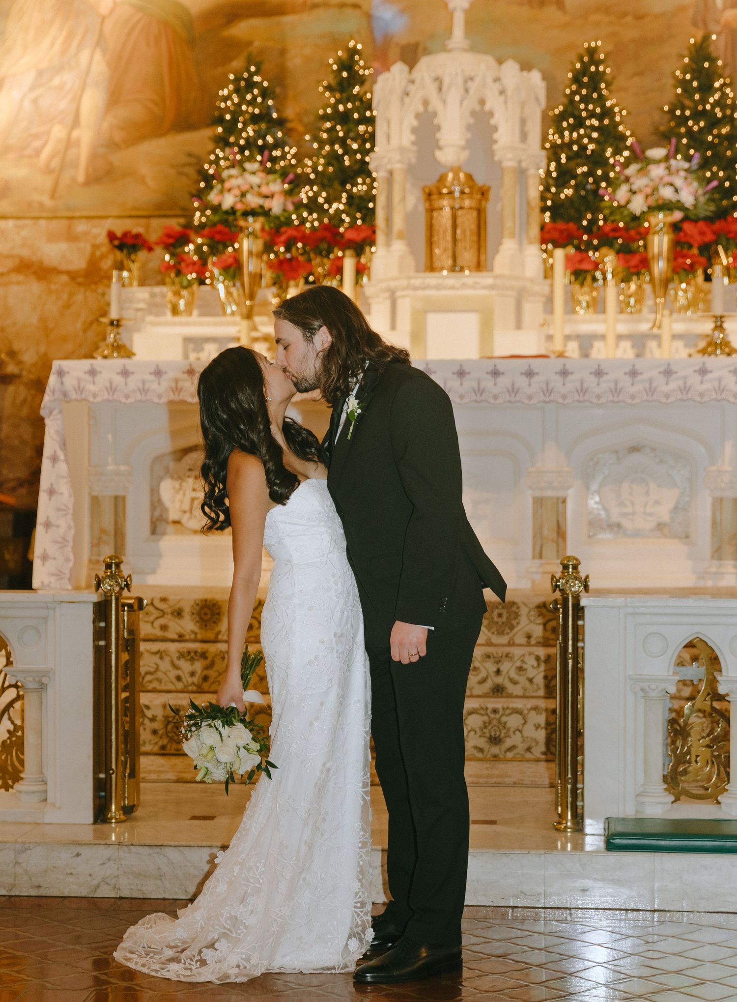 Wedding ceremony in beautifully decorated church with Christmas lights and white altar.