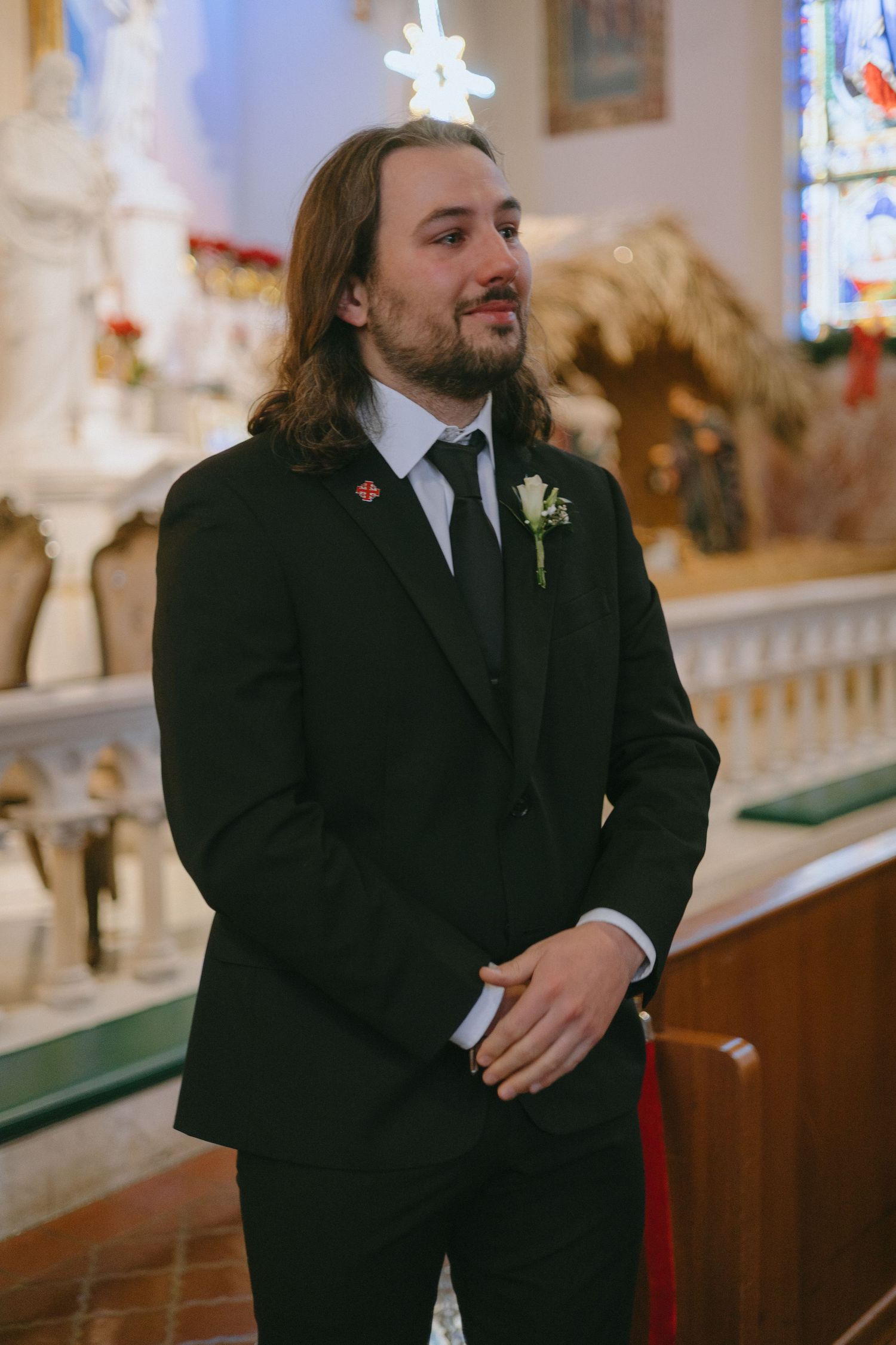 A groom shows emotional reaction during wedding ceremony in an ornate church setting.