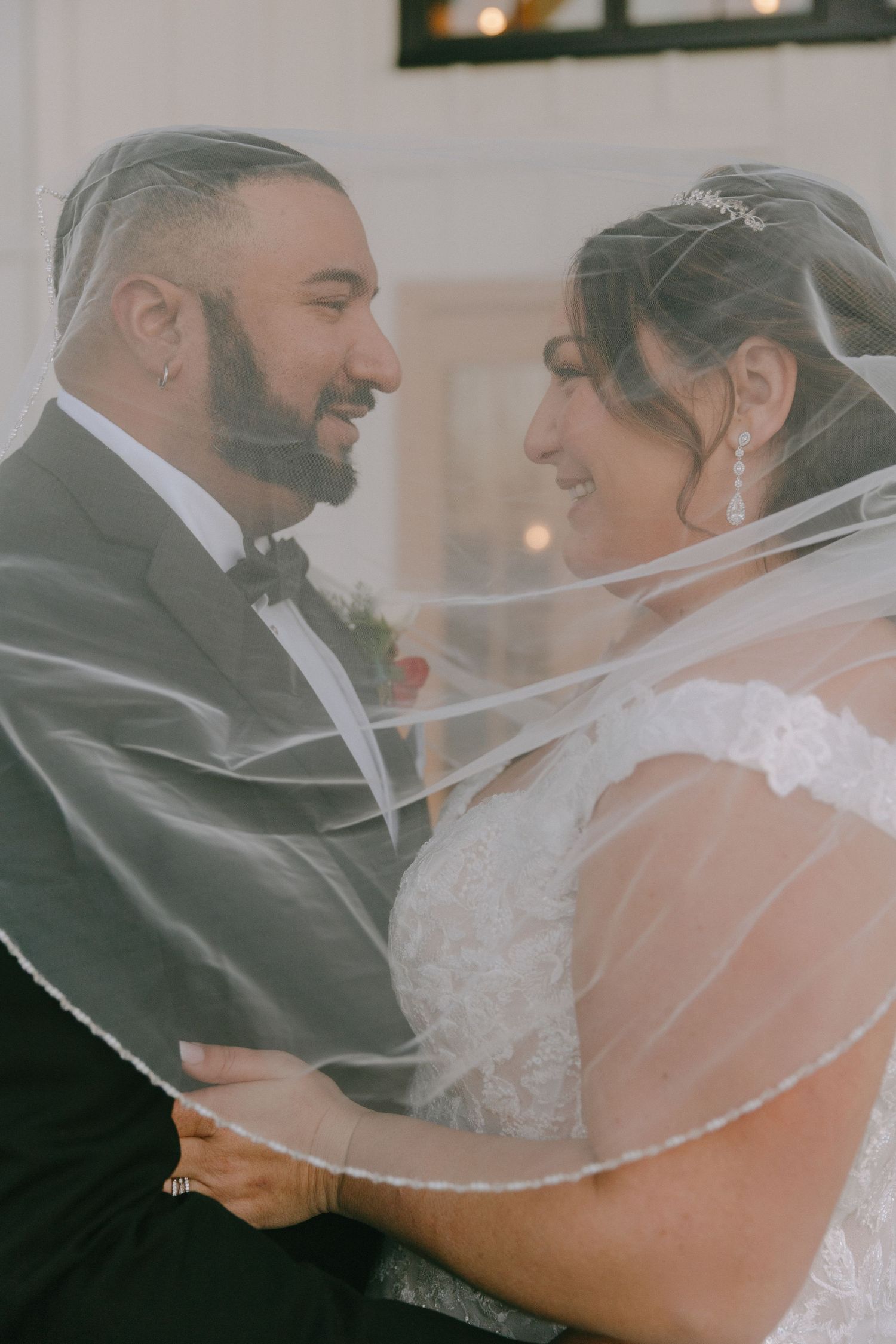 An intimate wedding portrait showing tender moments through a delicate veil.
