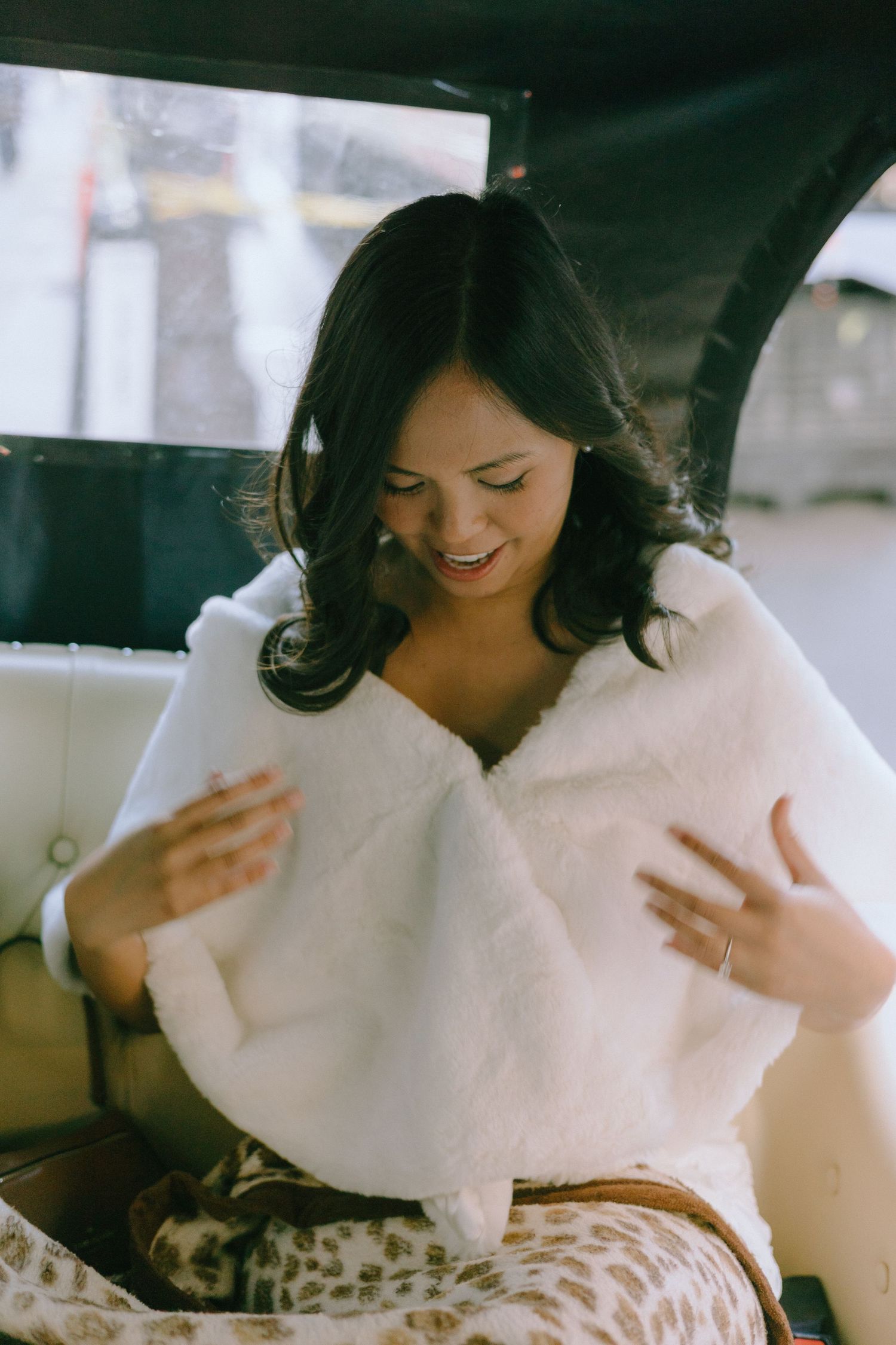 A bride in a white dress sits in a vintage car interior with elegant styling.