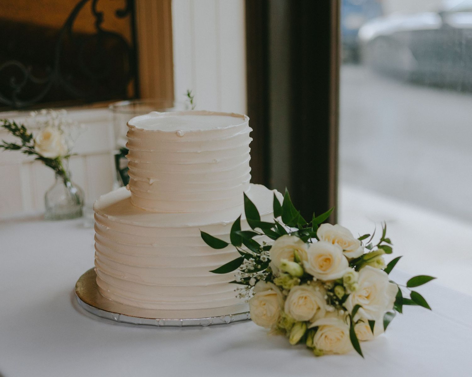 Elegant white wedding cake decorated with fresh flowers and textured frosting.
