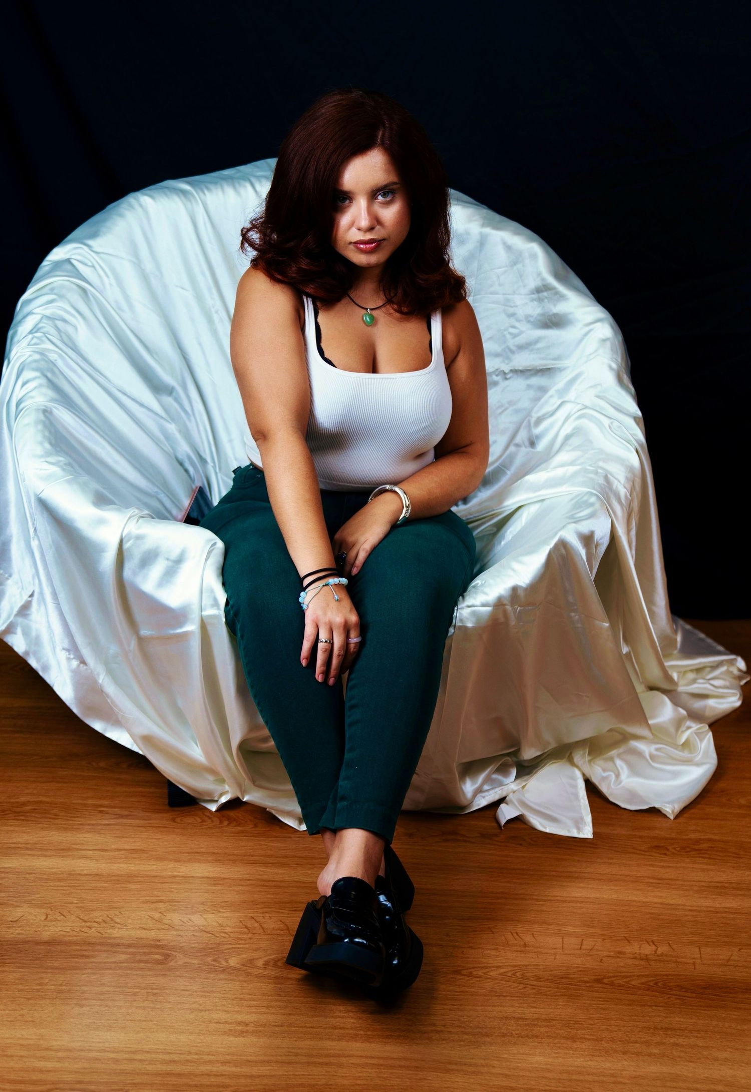Casual portrait seated in white chair wearing tank top and dark pants.